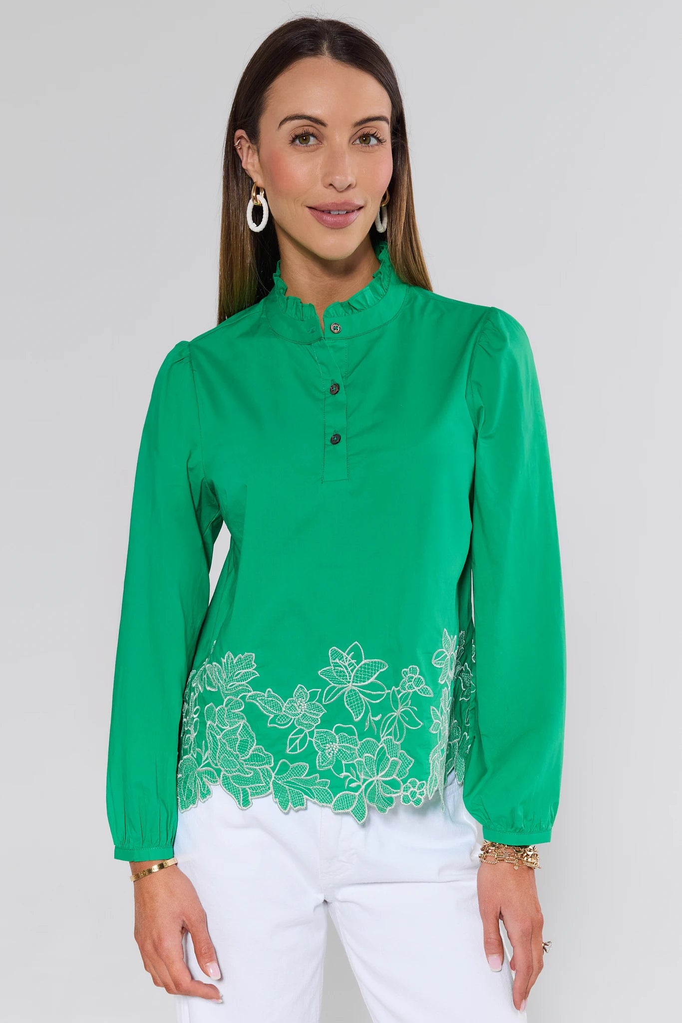 Woman wearing a green blouse with floral lace details on a white background