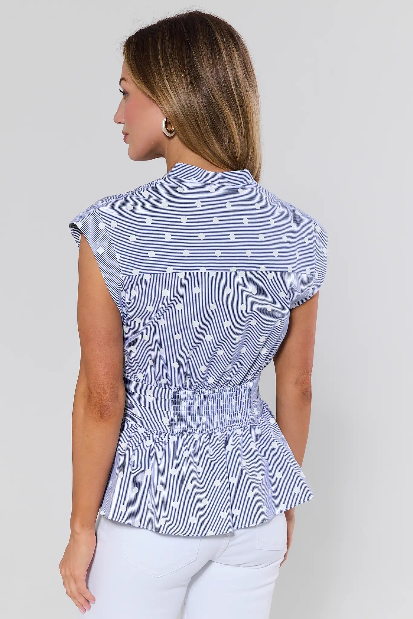 Woman wearing a blue polka dot blouse against a plain background