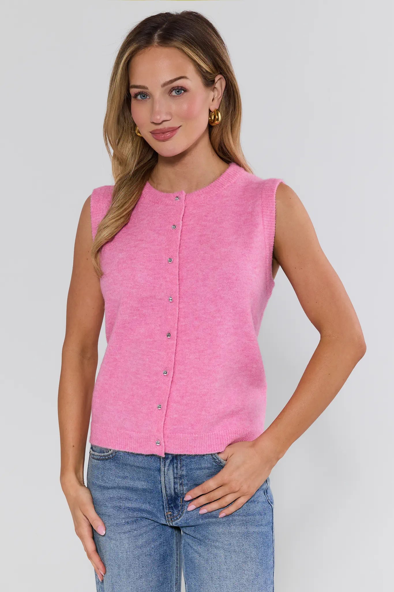 Woman wearing a pink sleeveless top with buttons against a white background