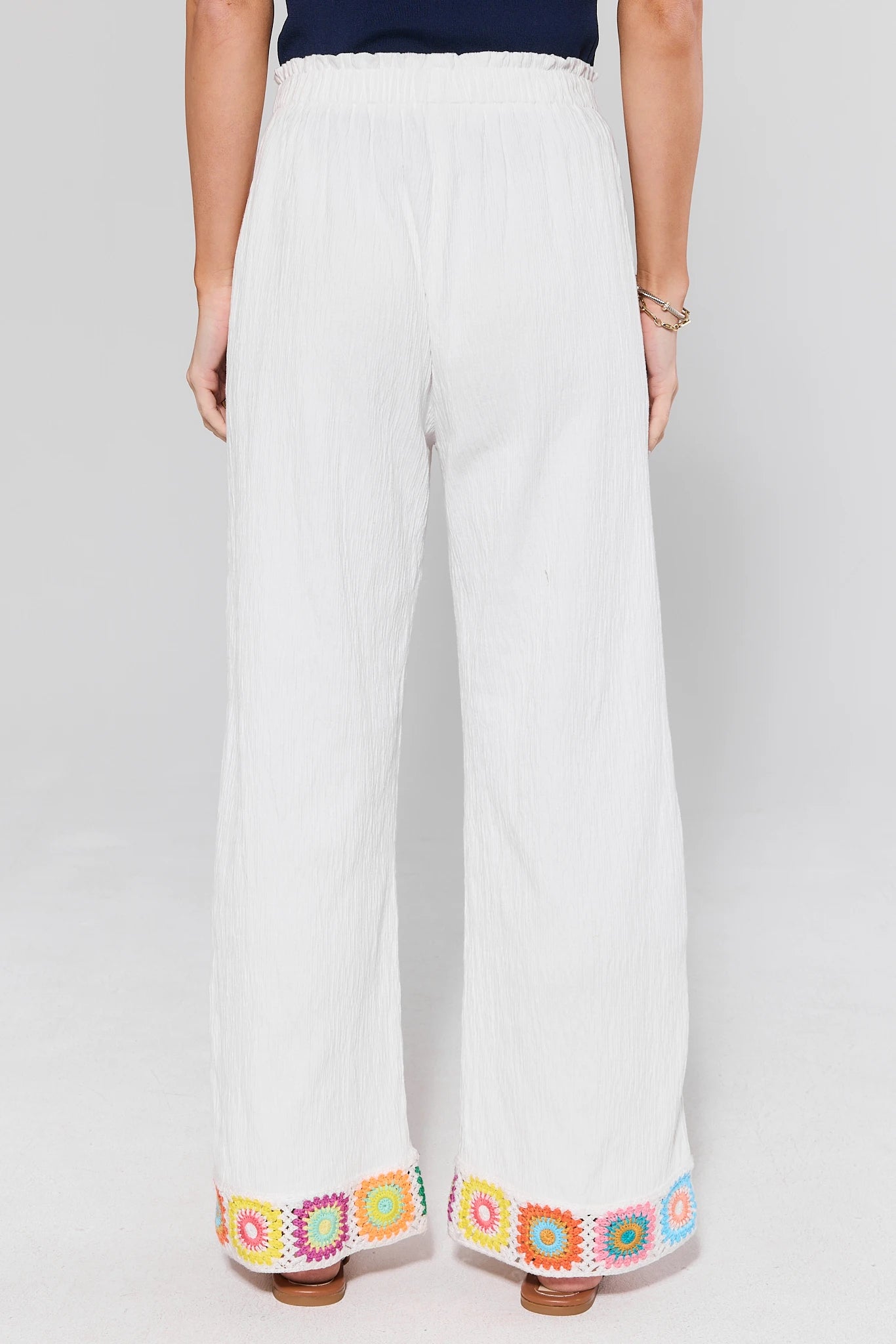 standing White pants with colorful embroidery at the bottom on a white background