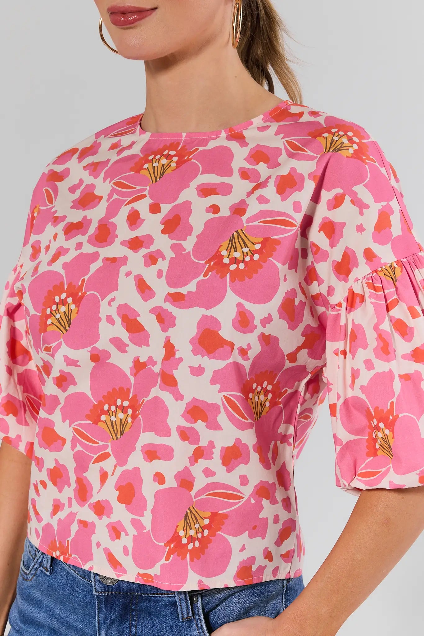 close up Woman wearing a pink floral blouse with a plain background
