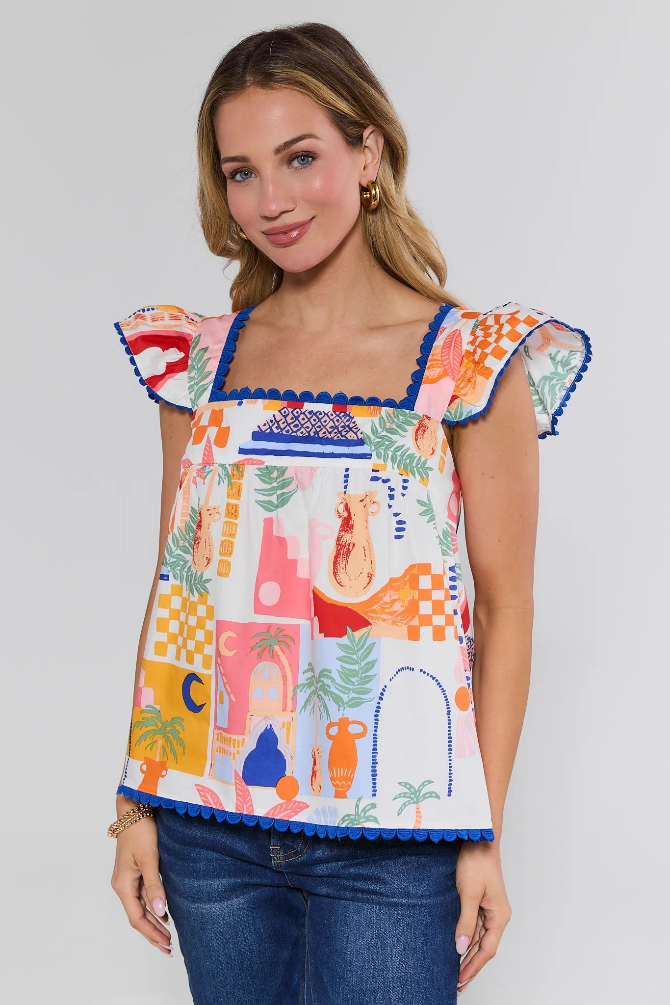 Woman wearing a colorful sleeveless top with abstract patterns on a plain background