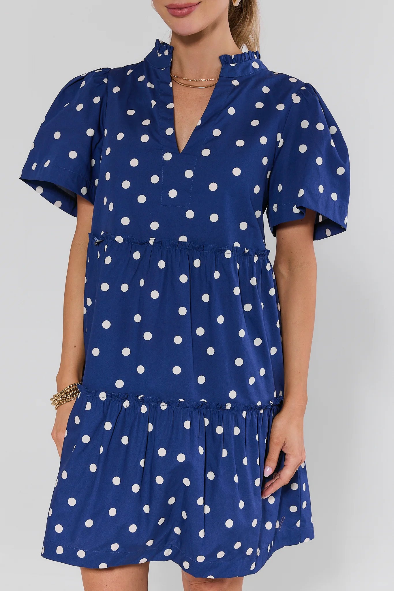 Woman wearing a blue dress with white polka dots on a plain background