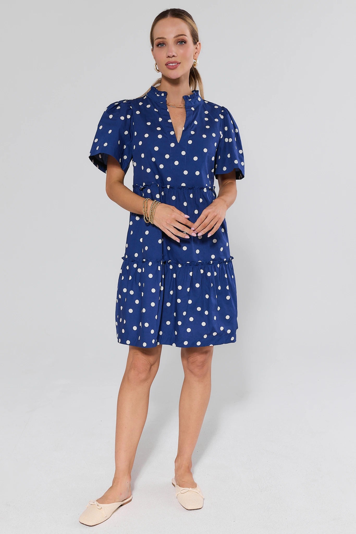 Woman wearing a blue dress with white polka dots on a background