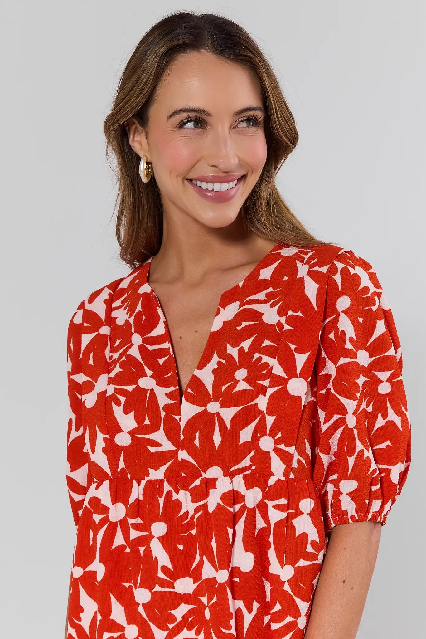 close up Woman wearing a red floral dress against a plain background