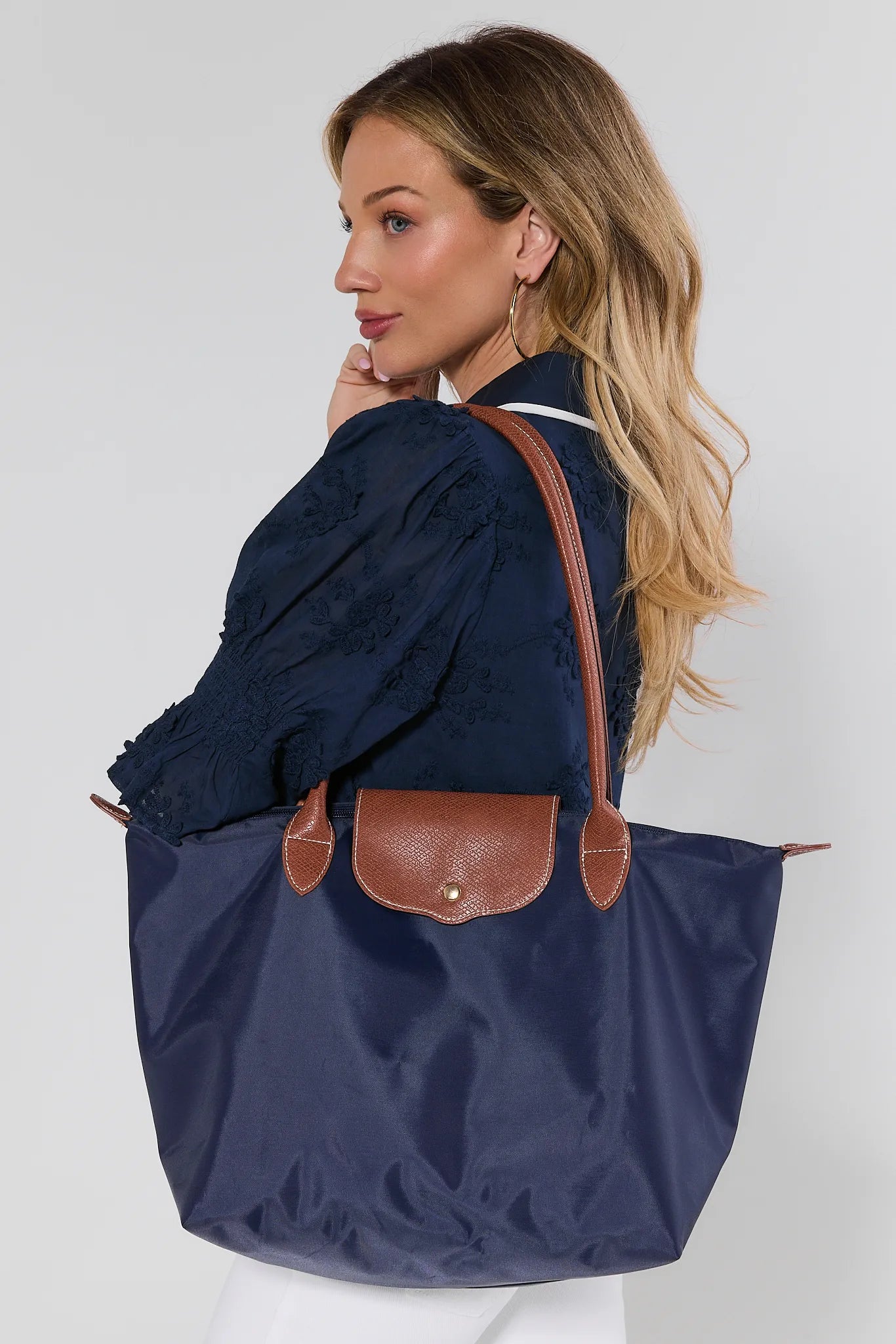 woman wearing navy tote bag on white background