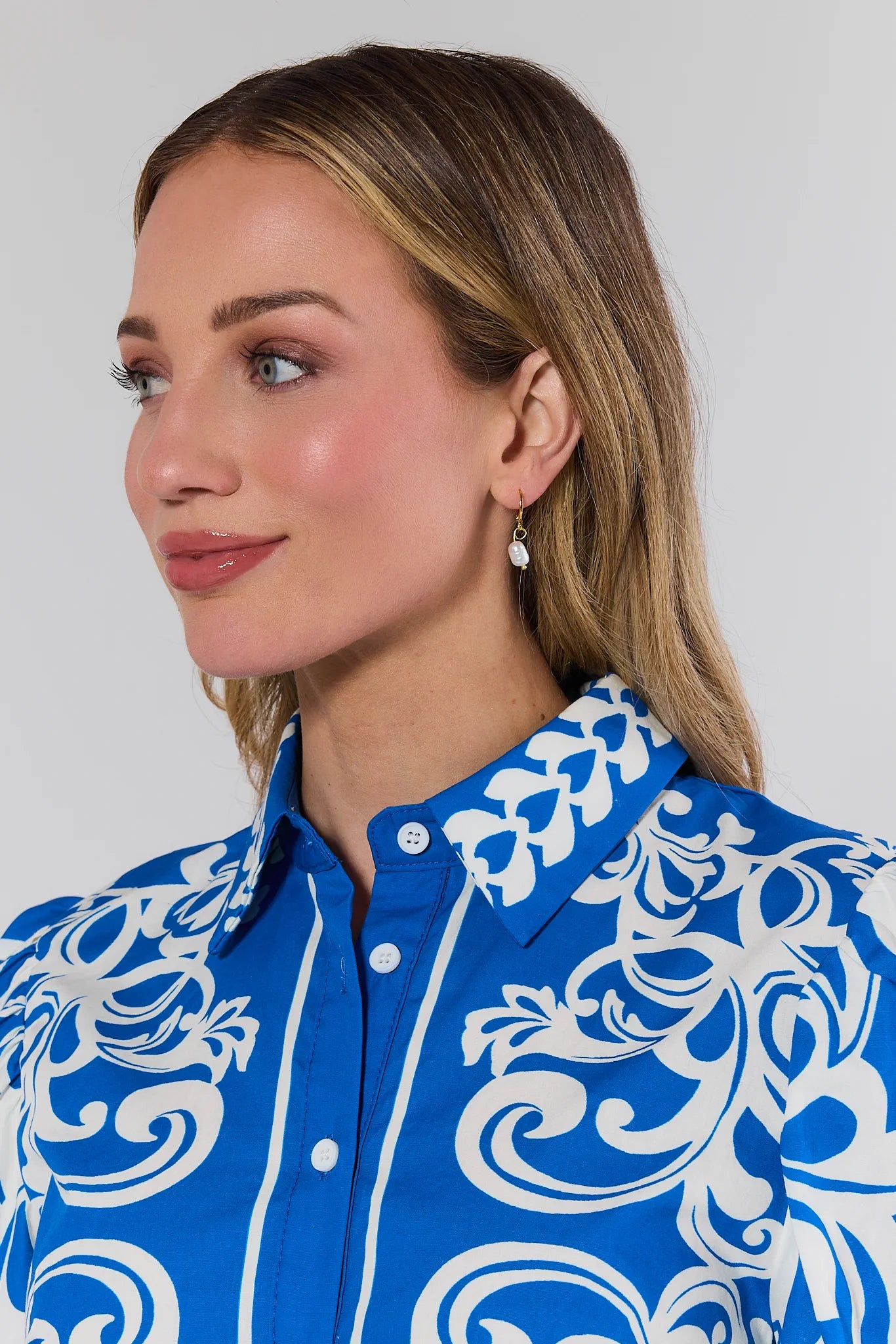 Woman wearing a blue shirt with white patterns against a plain background