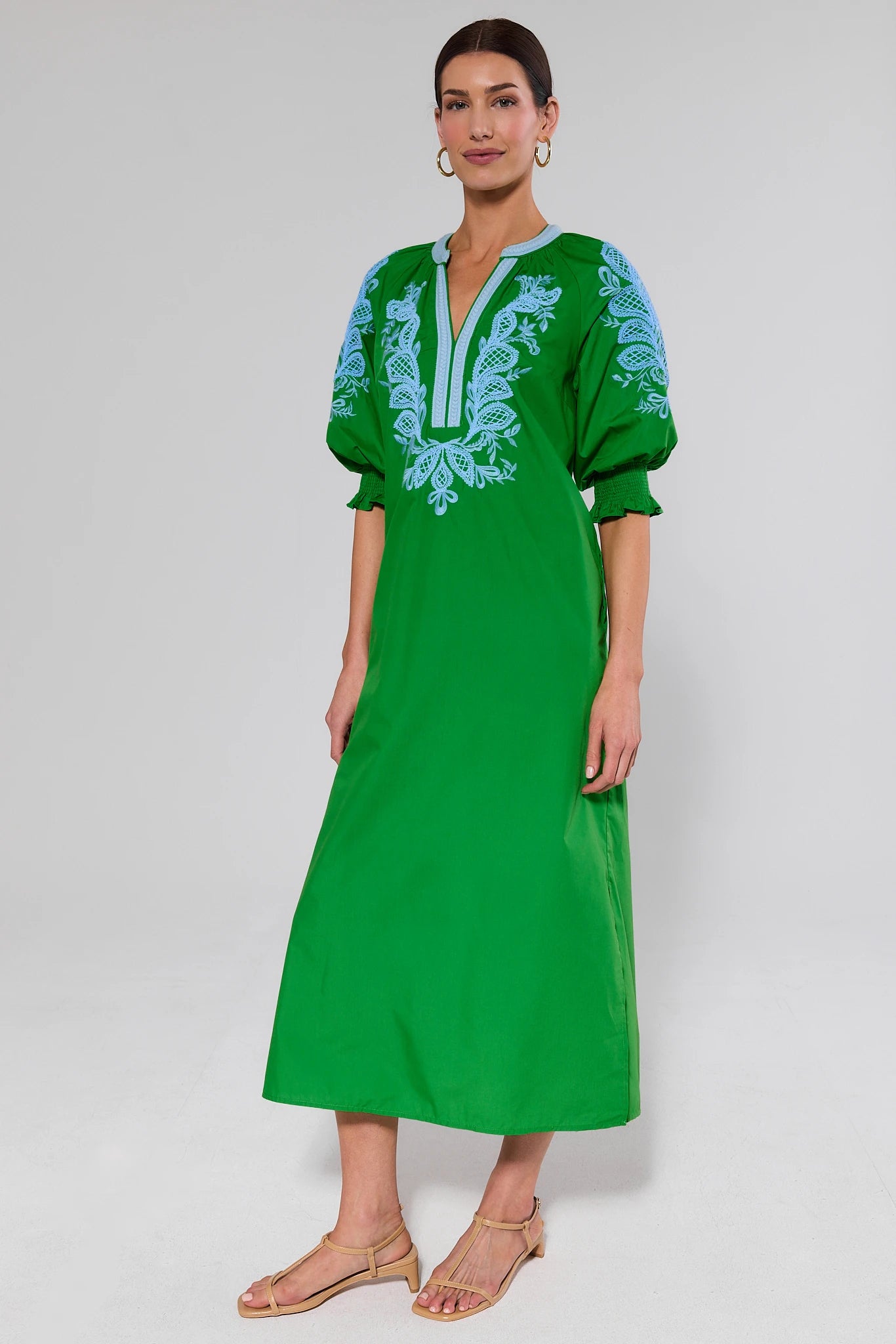 Woman wearing a green dress with blue embroidery on a background