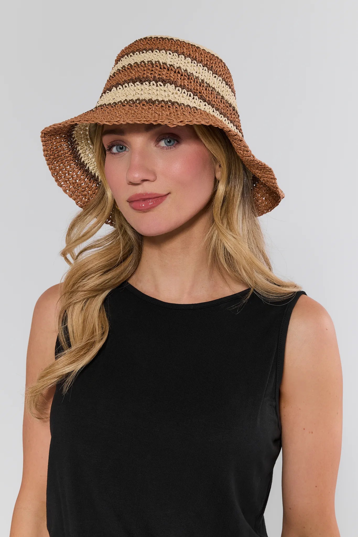 Woman wearing a striped straw hat against a plain background