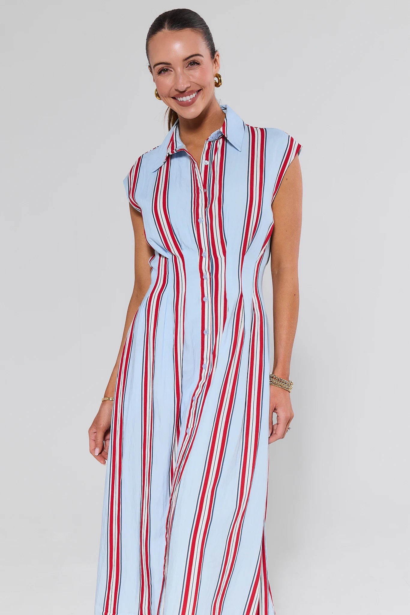 Woman wearing a sleeveless dress with red and white stripes on a plain background