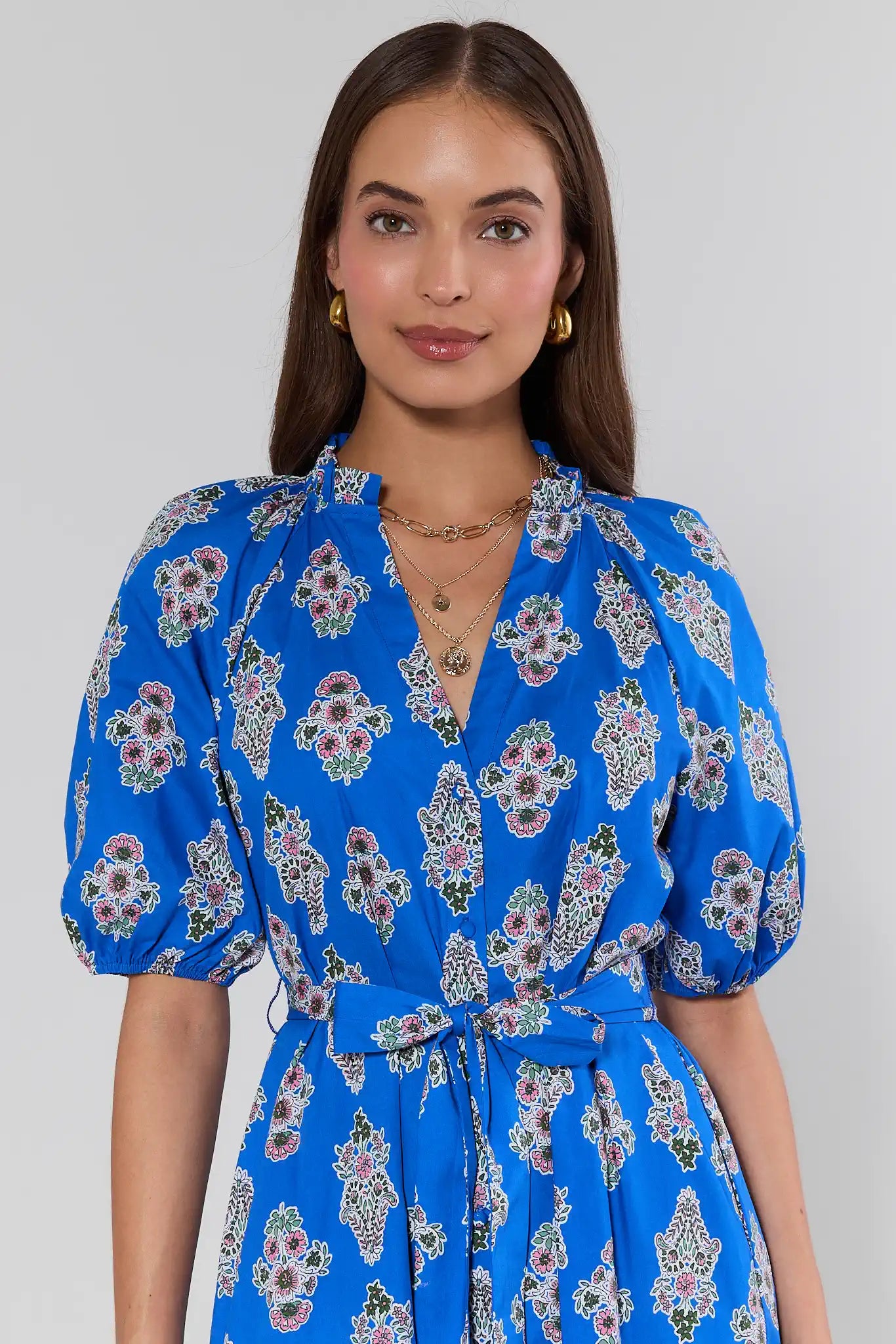 Woman wearing a blue floral dress against a plain background