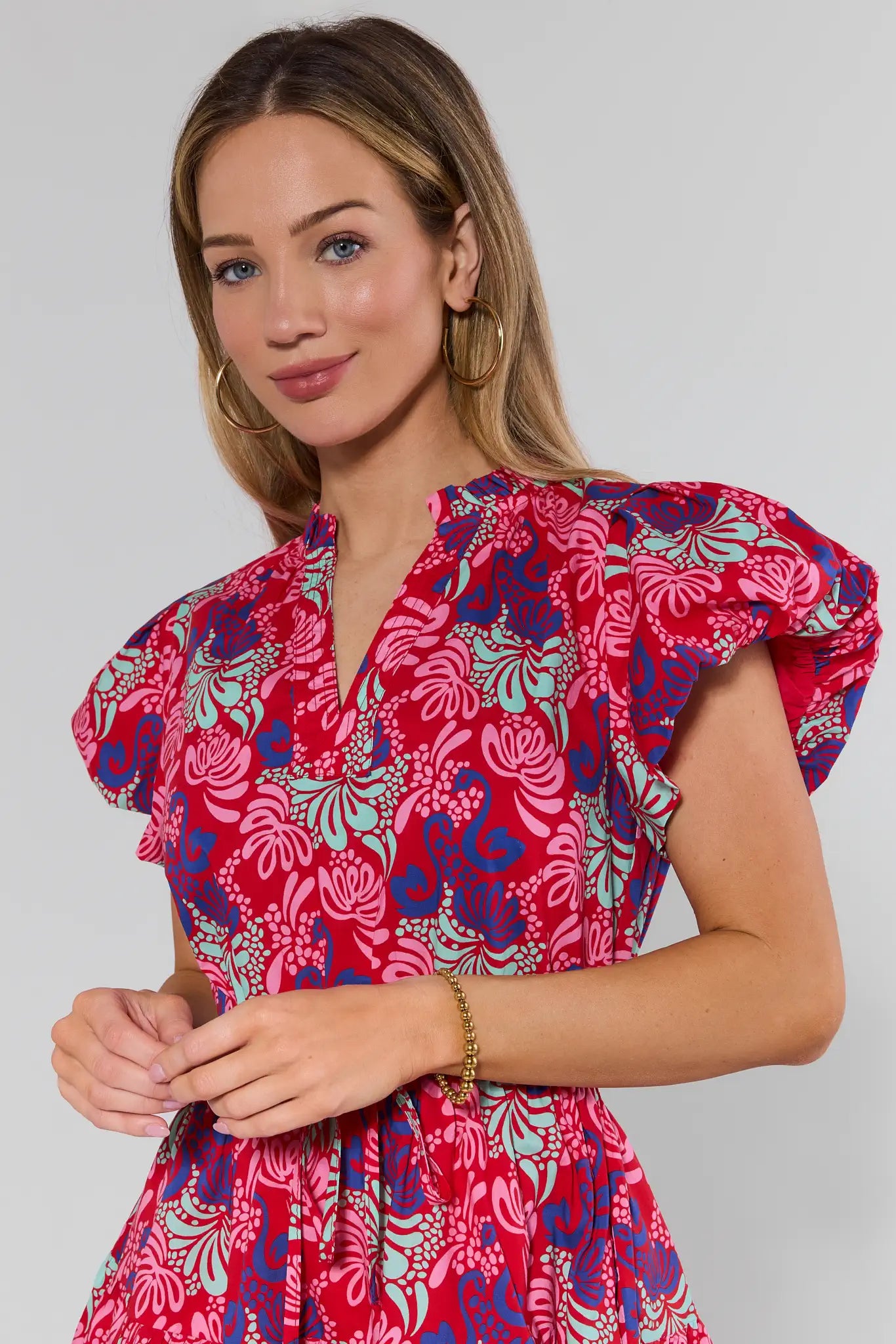 Woman wearing a colorful floral dress against a plain background