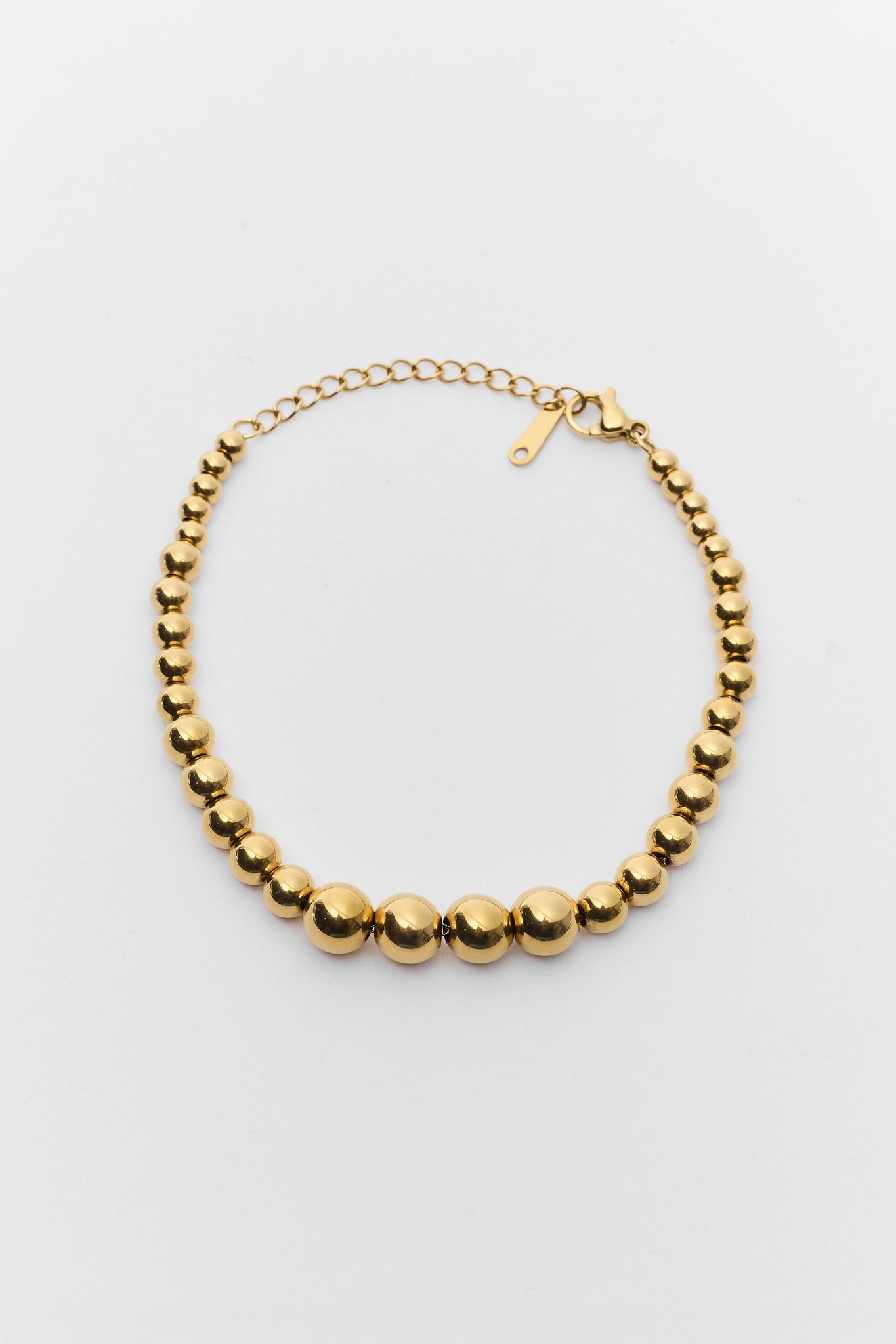 Gold beaded necklace on a light gray background