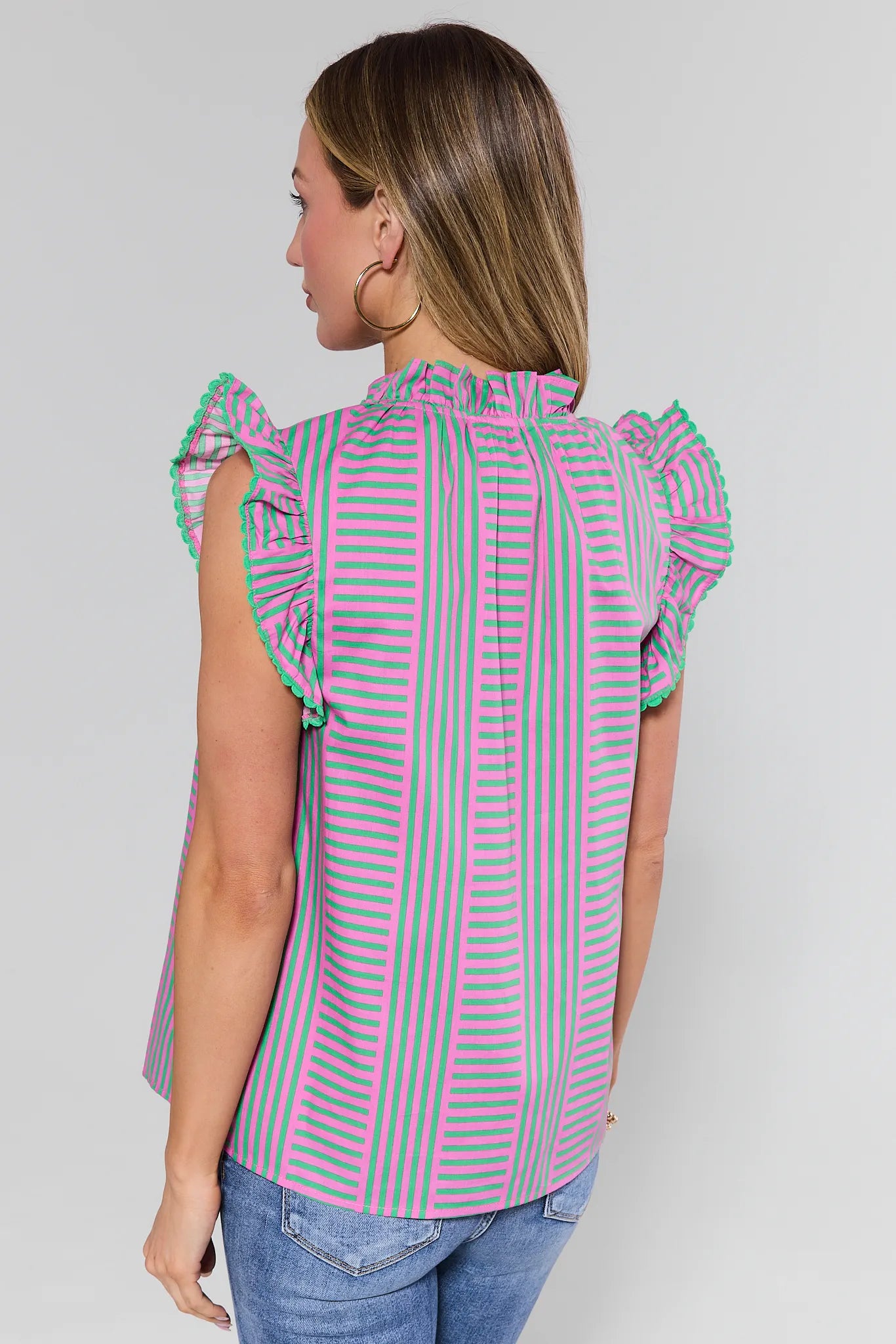 Woman wearing a striped shirt with ruffled sleeves on a plain background