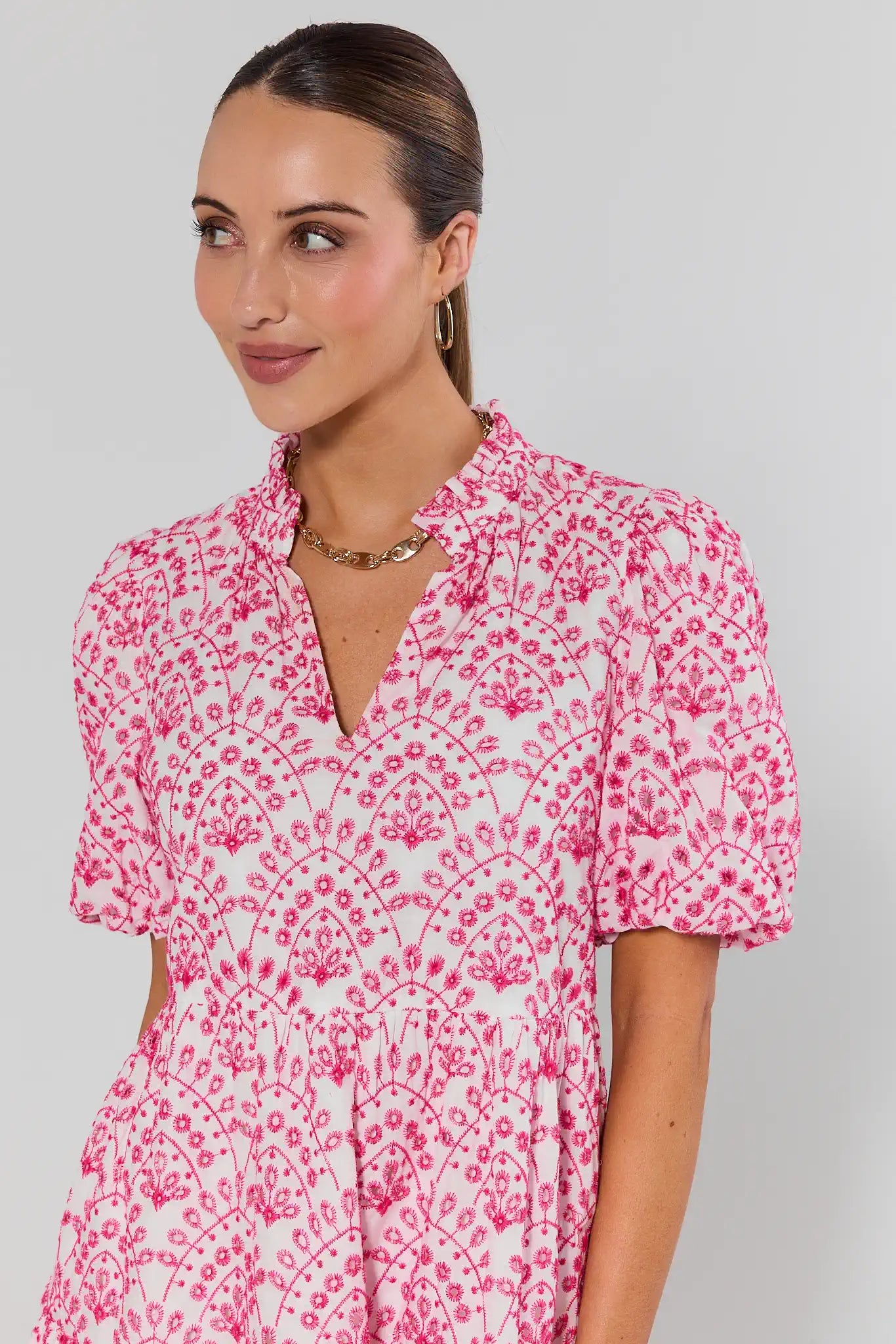 Woman wearing a pink and white patterned dress against a plain background