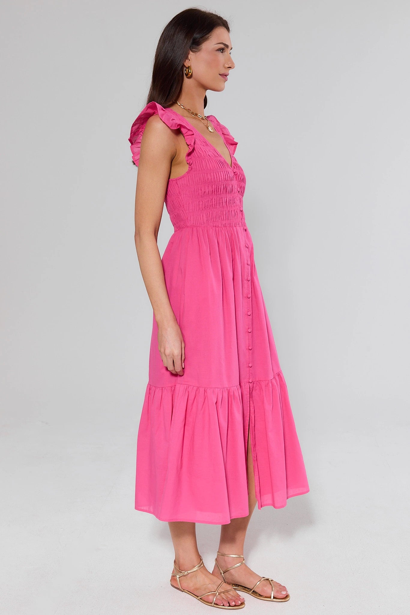 side shot Woman wearing a pink dress with ruffled sleeves on a white background
