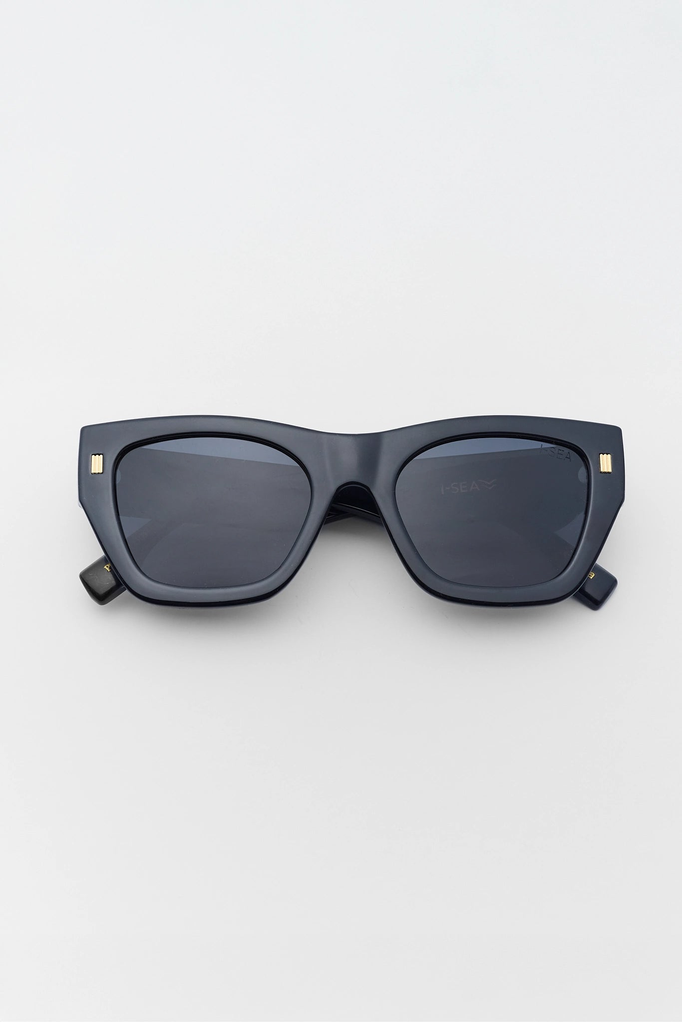 Black sunglasses with gold accents on a light gray background