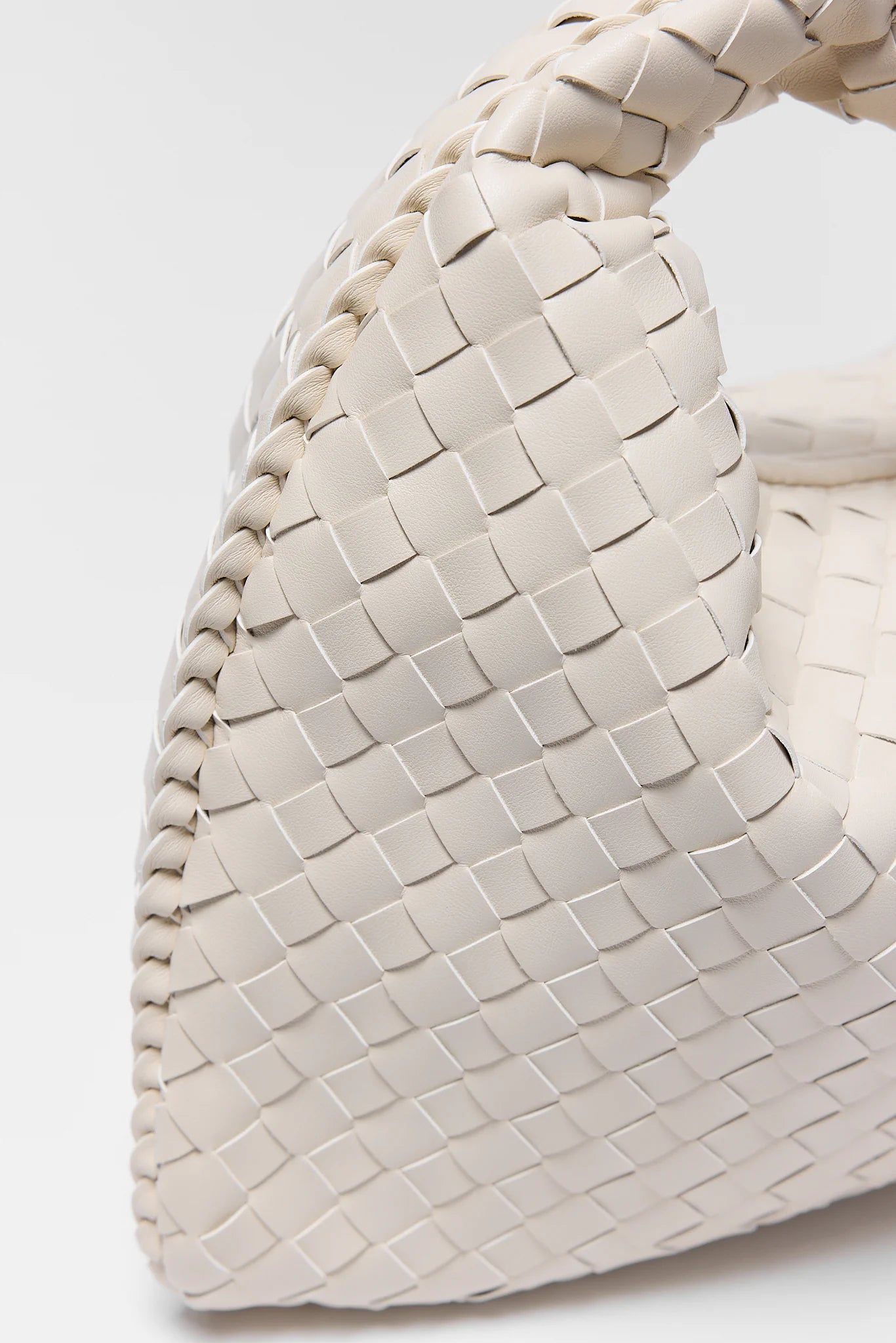 Close-up of a woven beige handbag on a white background