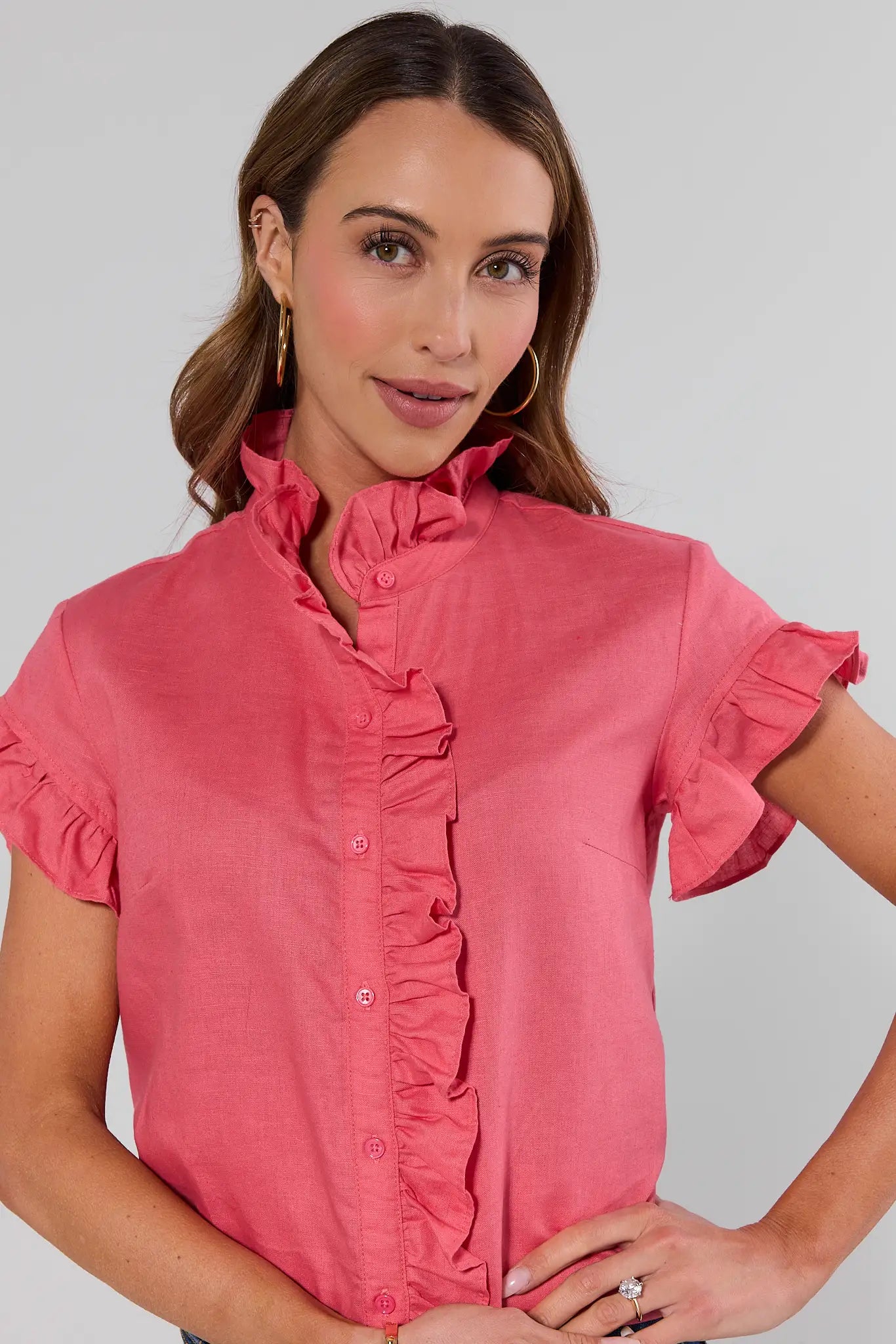 close up Woman wearing a pink blouse with ruffled details on a gray background