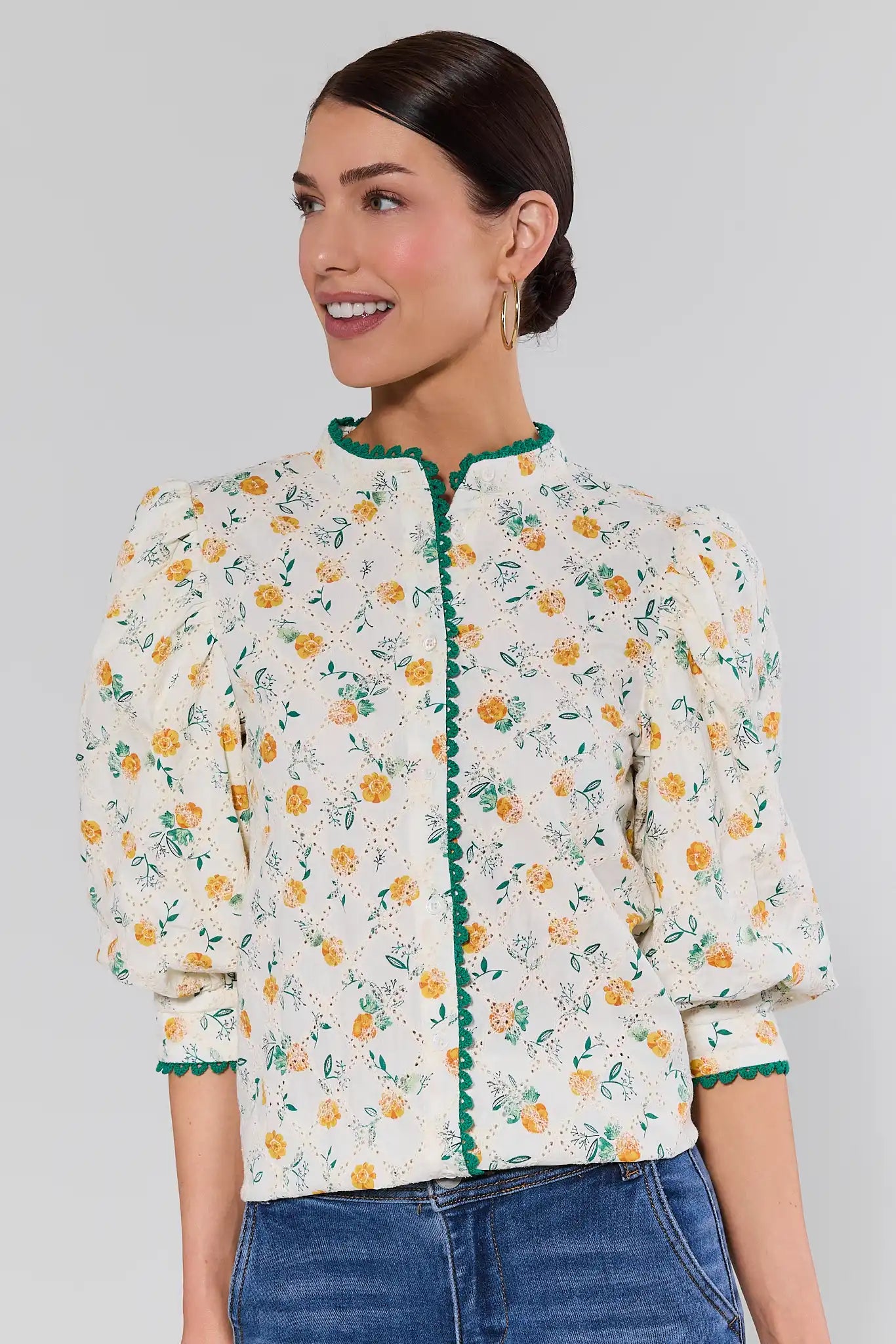 Woman wearing a floral blouse with green trim on a gray background