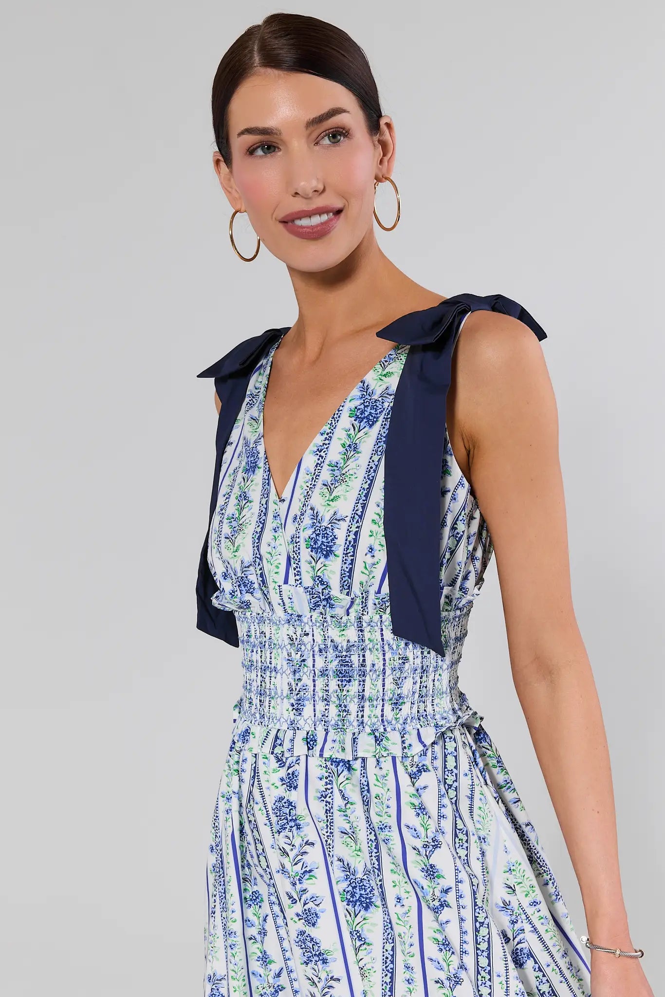 close up Woman wearing a floral dress with a blue bow detail on a gray background