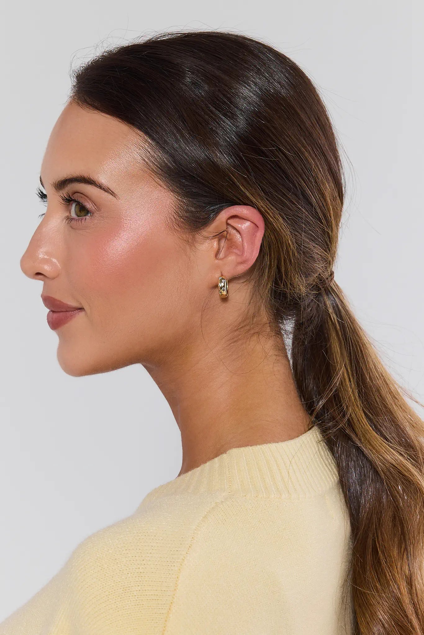 Woman with a side ponytail wearing a yellow top against a plain background