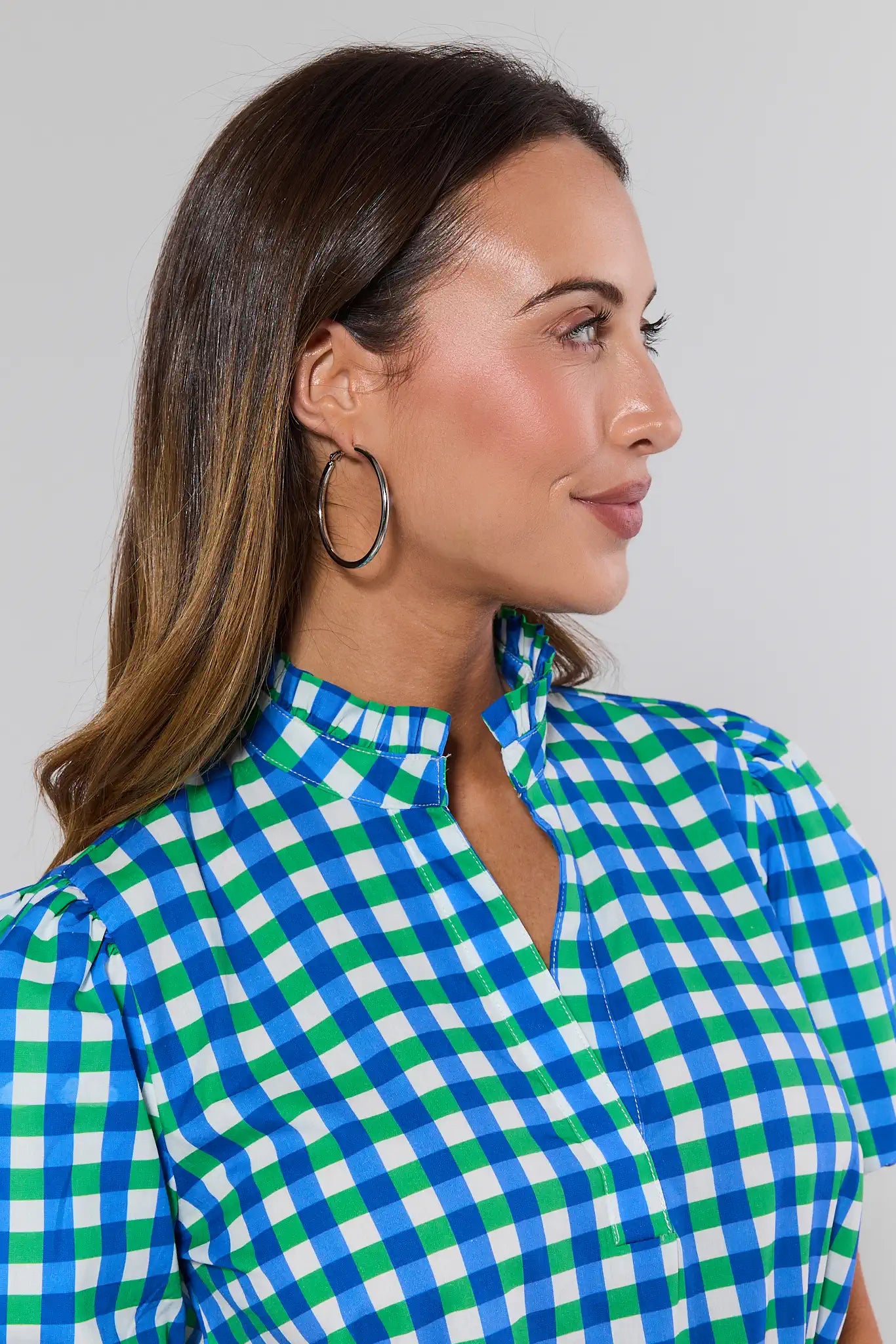 Woman wearing a blue and green checkered shirt against a plain background