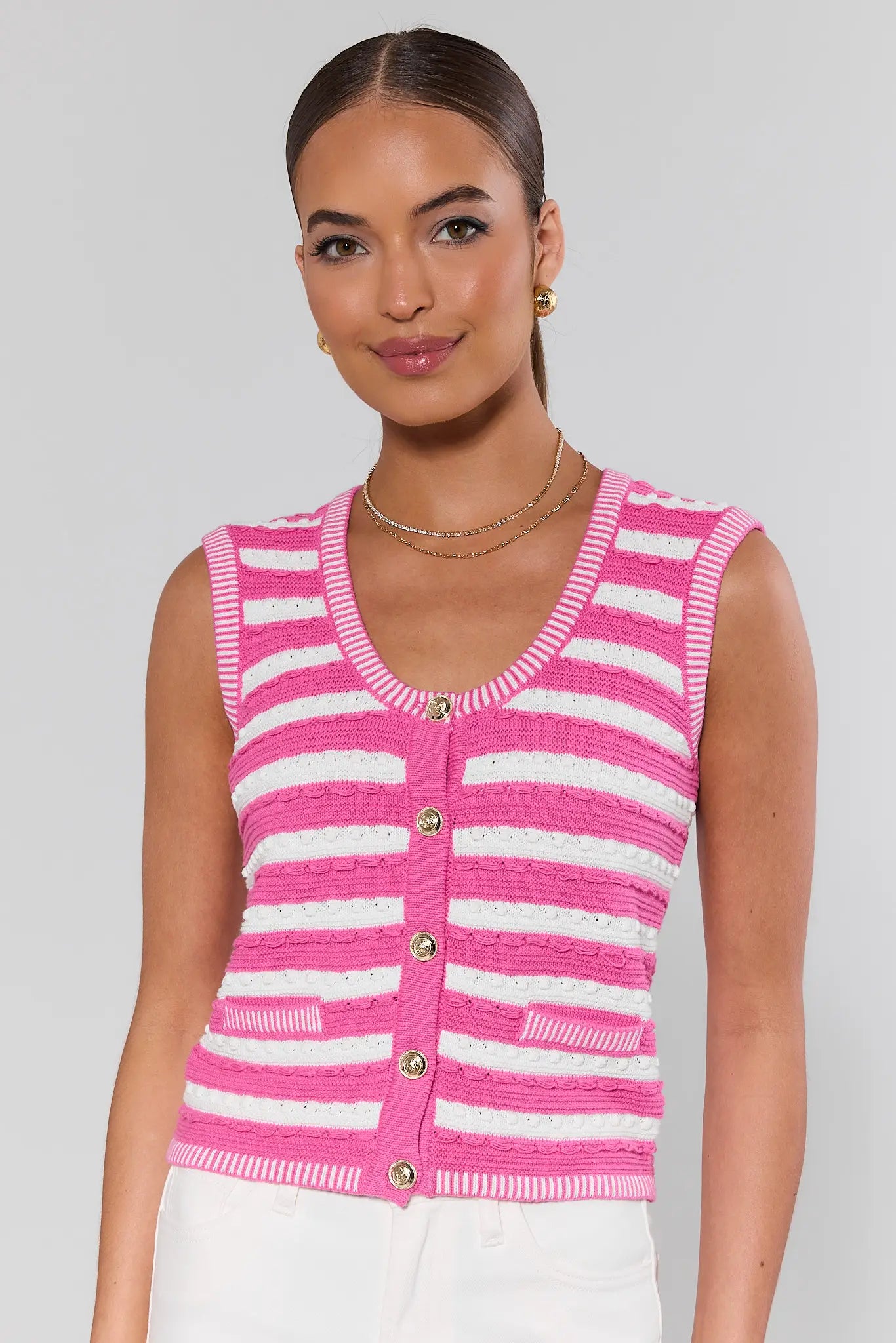 Woman wearing a pink and white striped sleeveless cardigan on a plain background