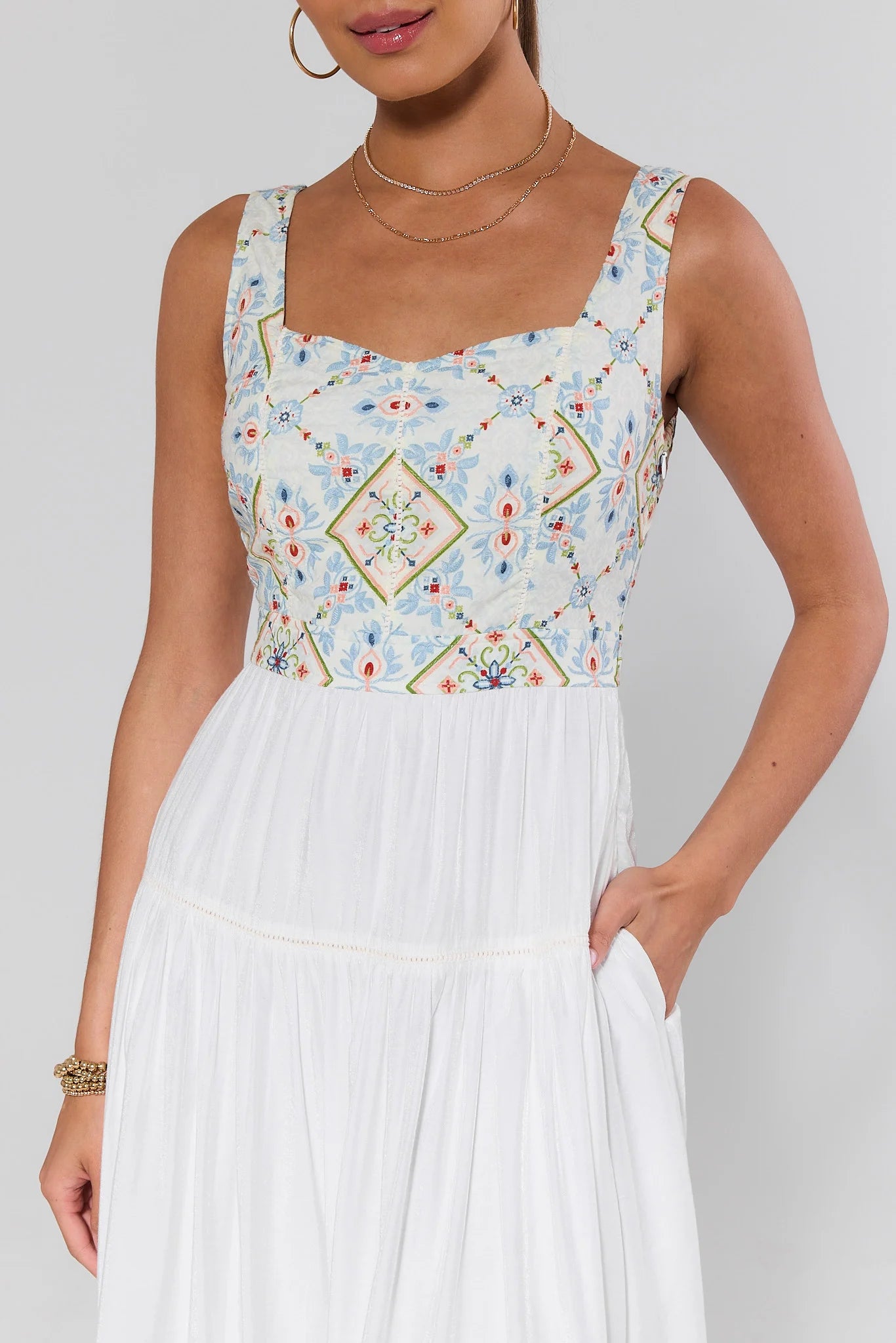 close up Woman wearing a sleeveless dress with a floral pattern on a plain background