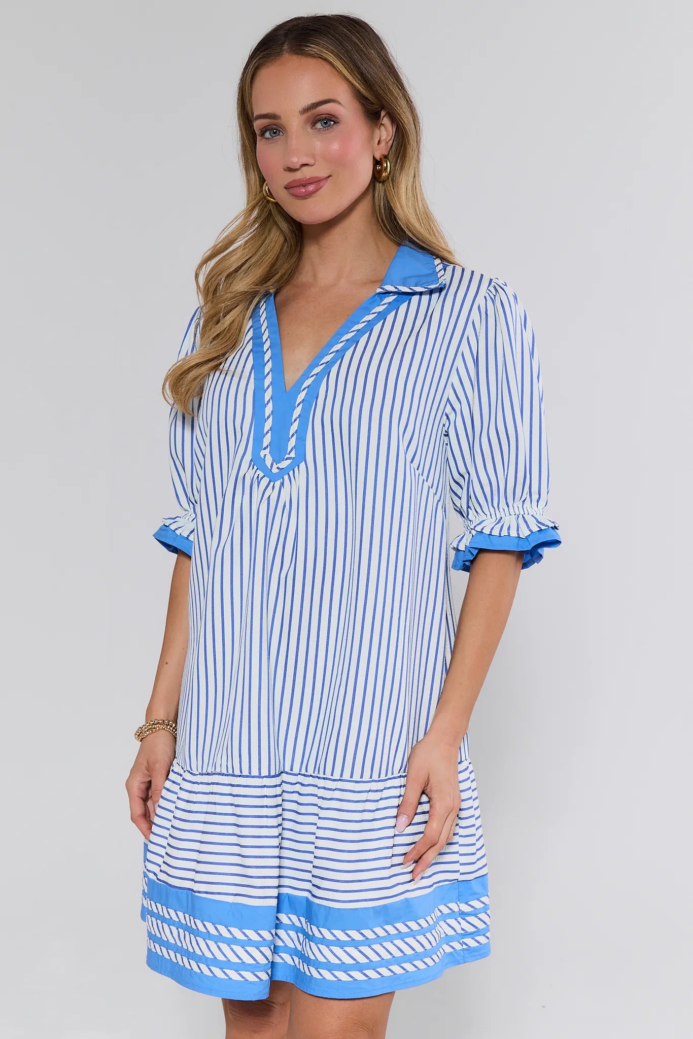 Woman wearing a blue and white striped dress on a gray background
