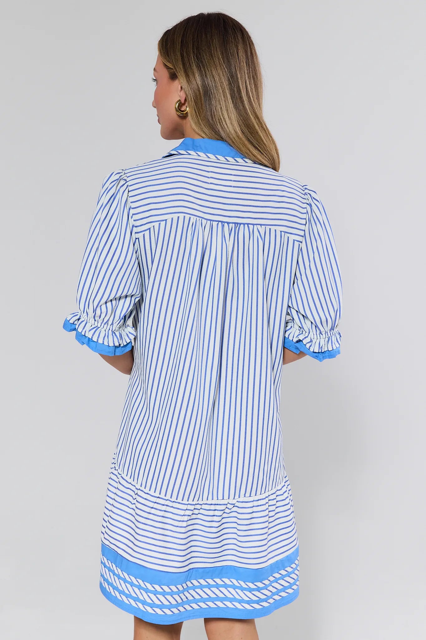 Woman wearing a blue and white striped dress with a plain background