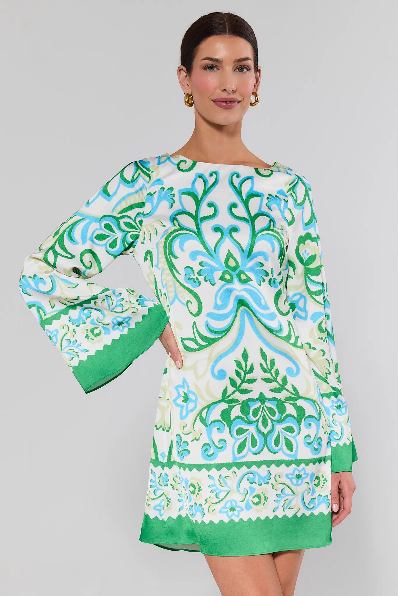 Woman wearing a green and blue patterned dress on a gray background