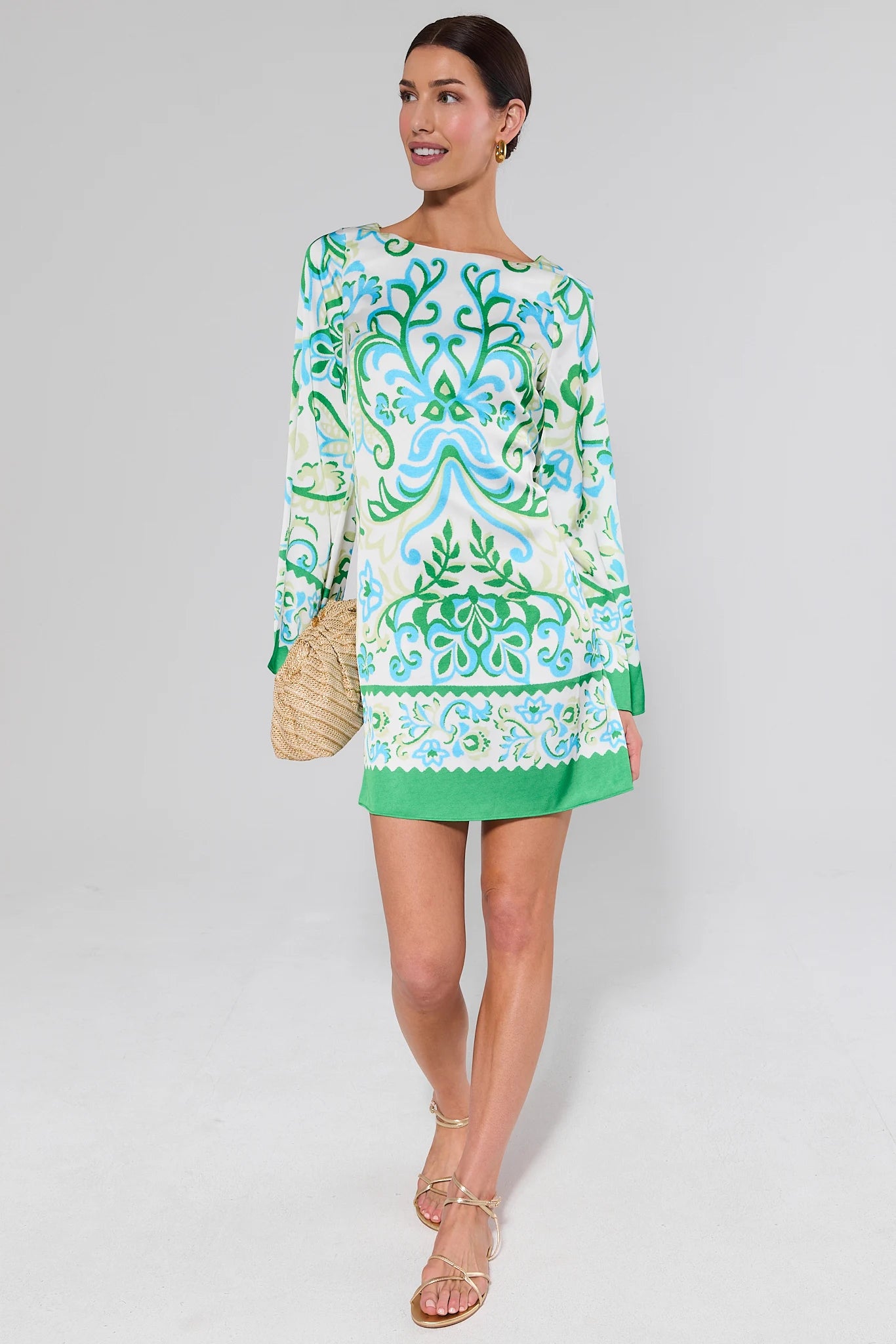 Woman wearing a arabella green and blue patterned dress on a white background