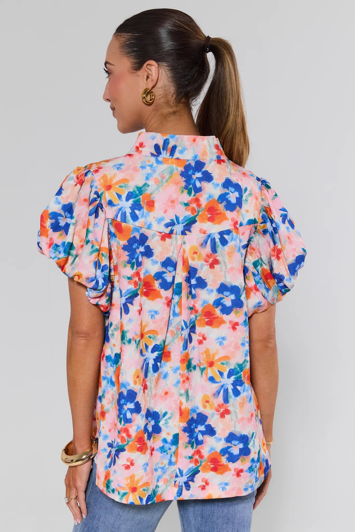 Woman wearing a colorful floral blouse against a plain background