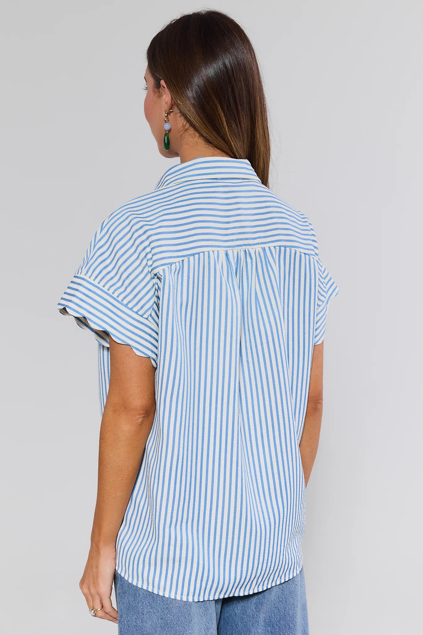 Woman wearing a blue and white striped shirt against a plain background