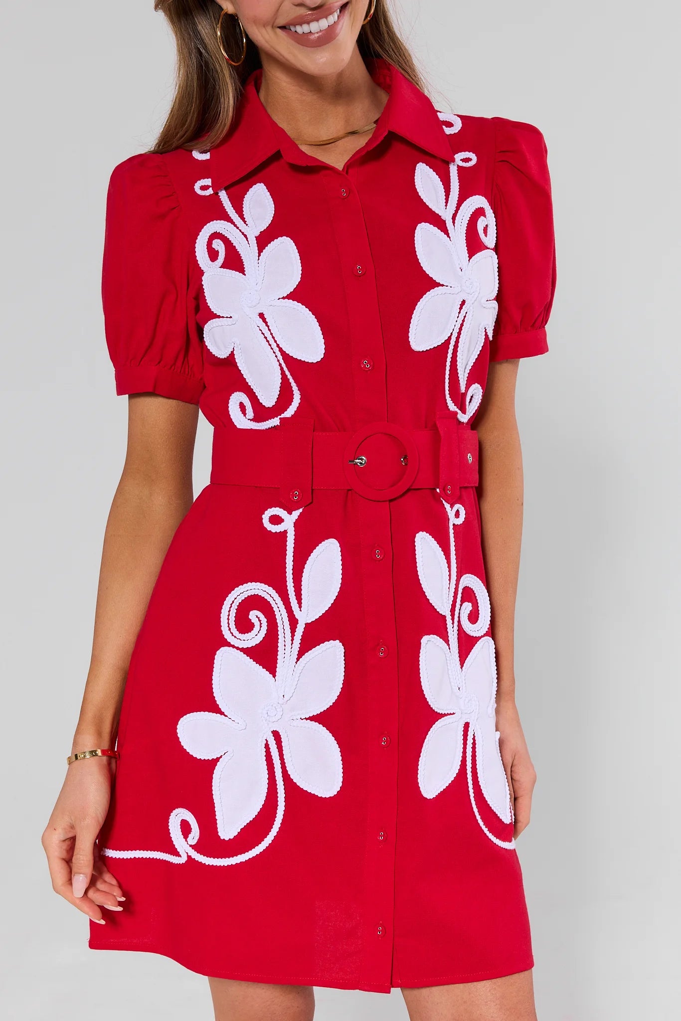 close up Red dress with white floral patterns worn by a model against a gray background