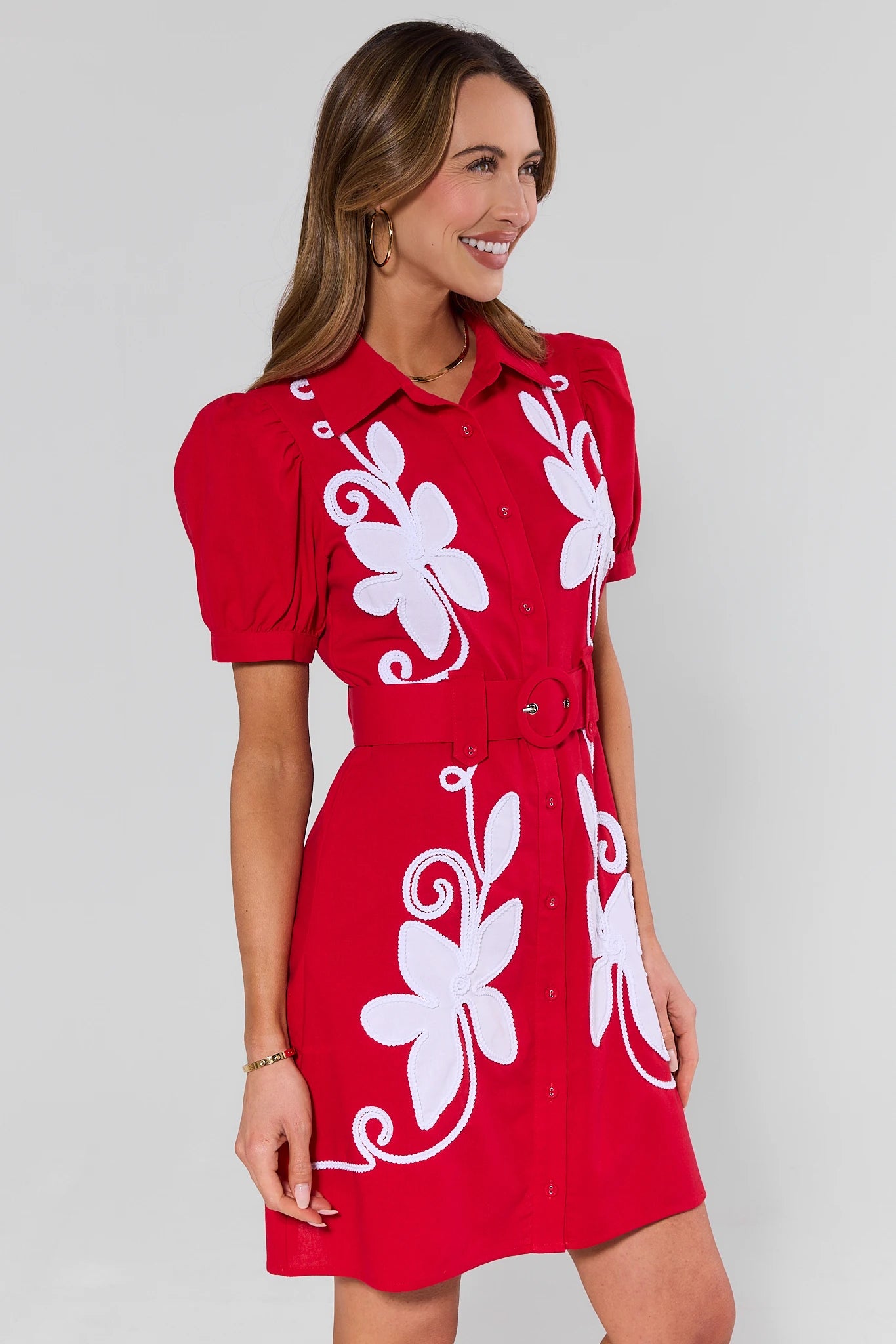 side shot Woman wearing a red dress with white floral patterns on a plain background