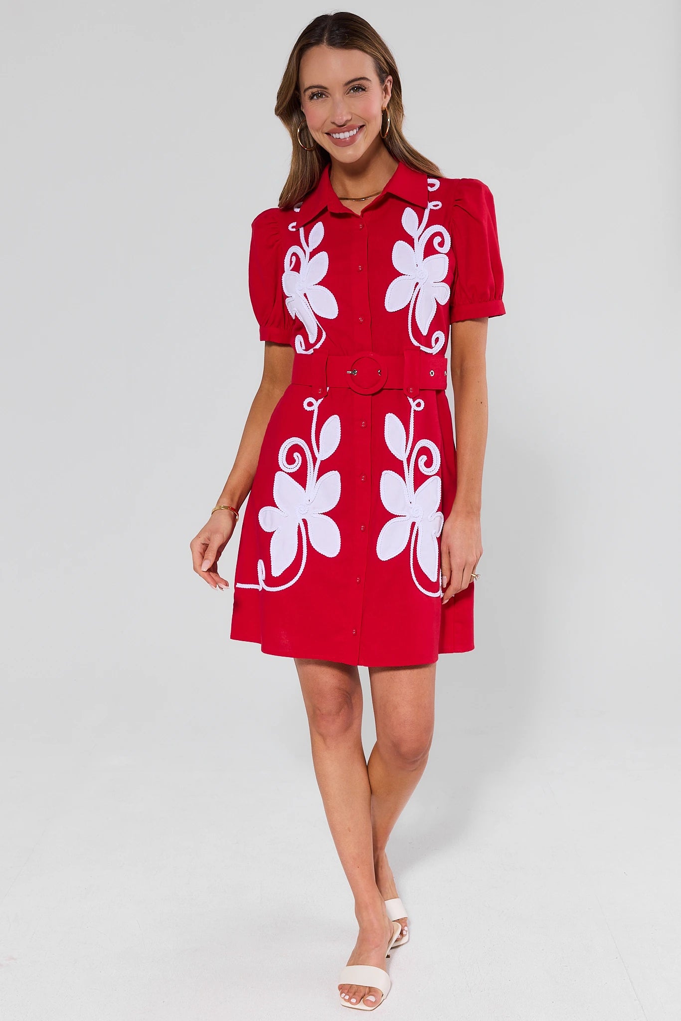 Woman wearing a red dress with white floral patterns and heels on a white background