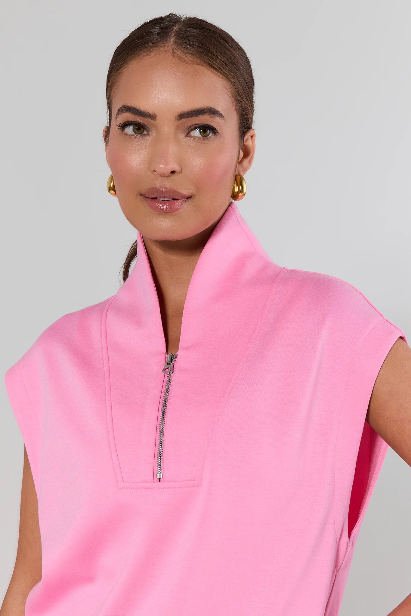 close up Woman wearing a pink sleeveless top with a zipper on a gray background