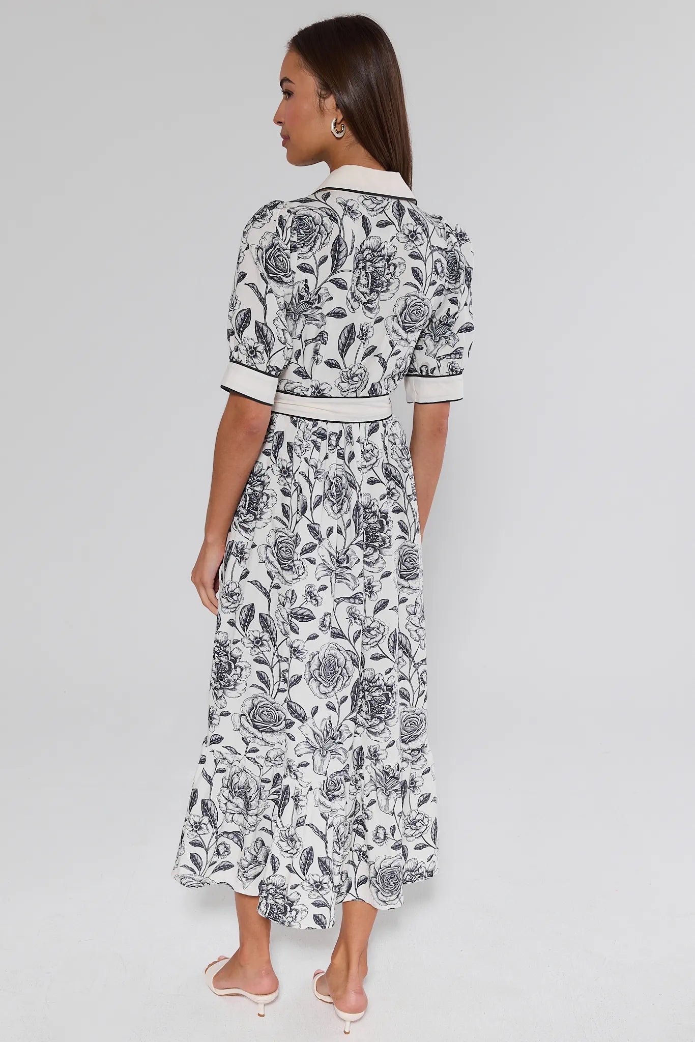 Woman wearing a black and white floral dress on a gray background