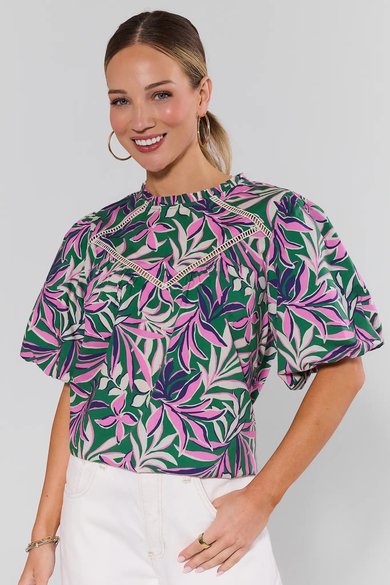 Woman wearing a colorful leaf-patterned blouse against a plain background