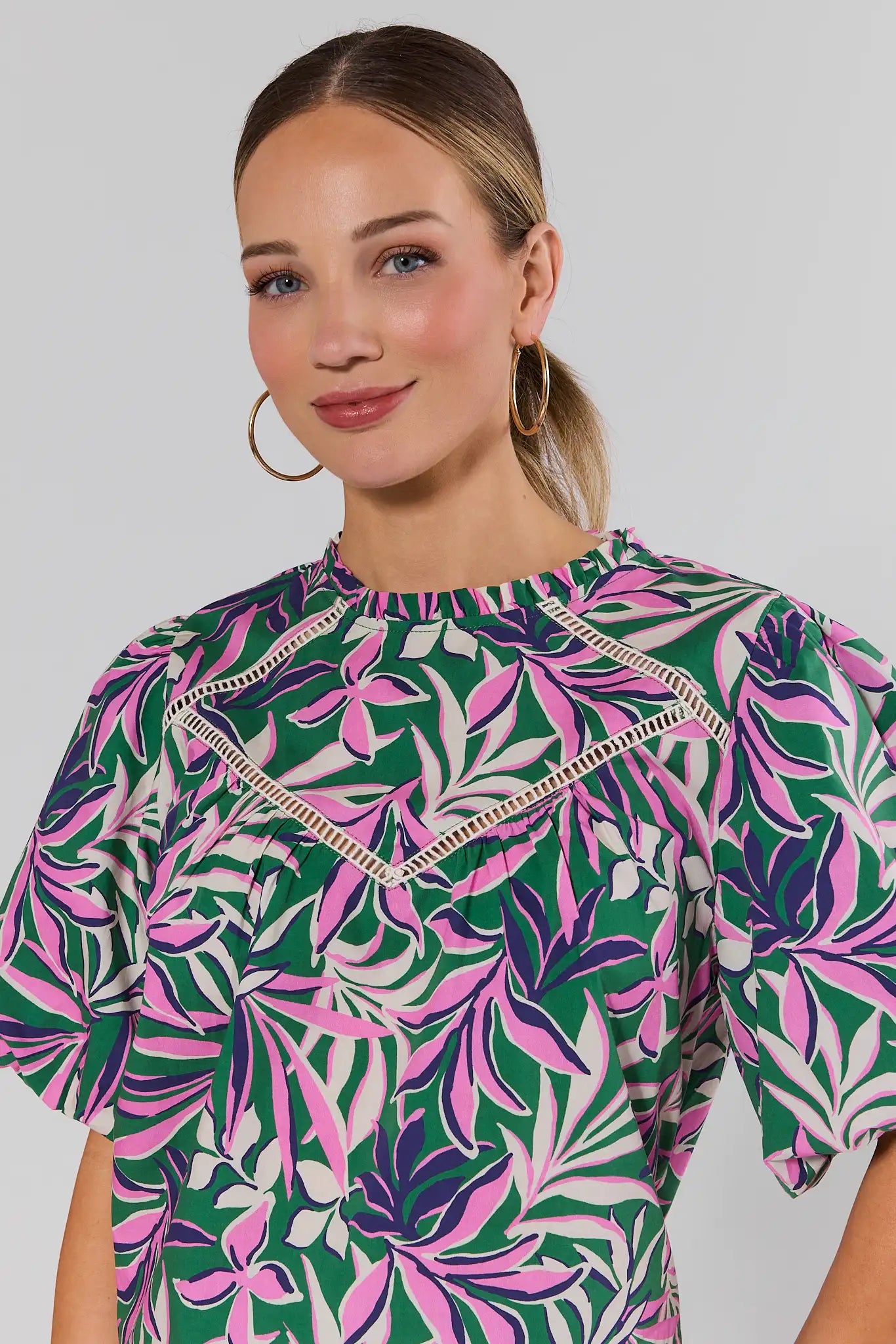 close up Woman wearing a colorful floral dress against a plain background
