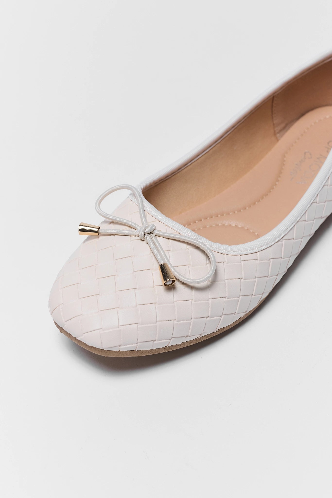 White flat shoe with a bow on a light gray background