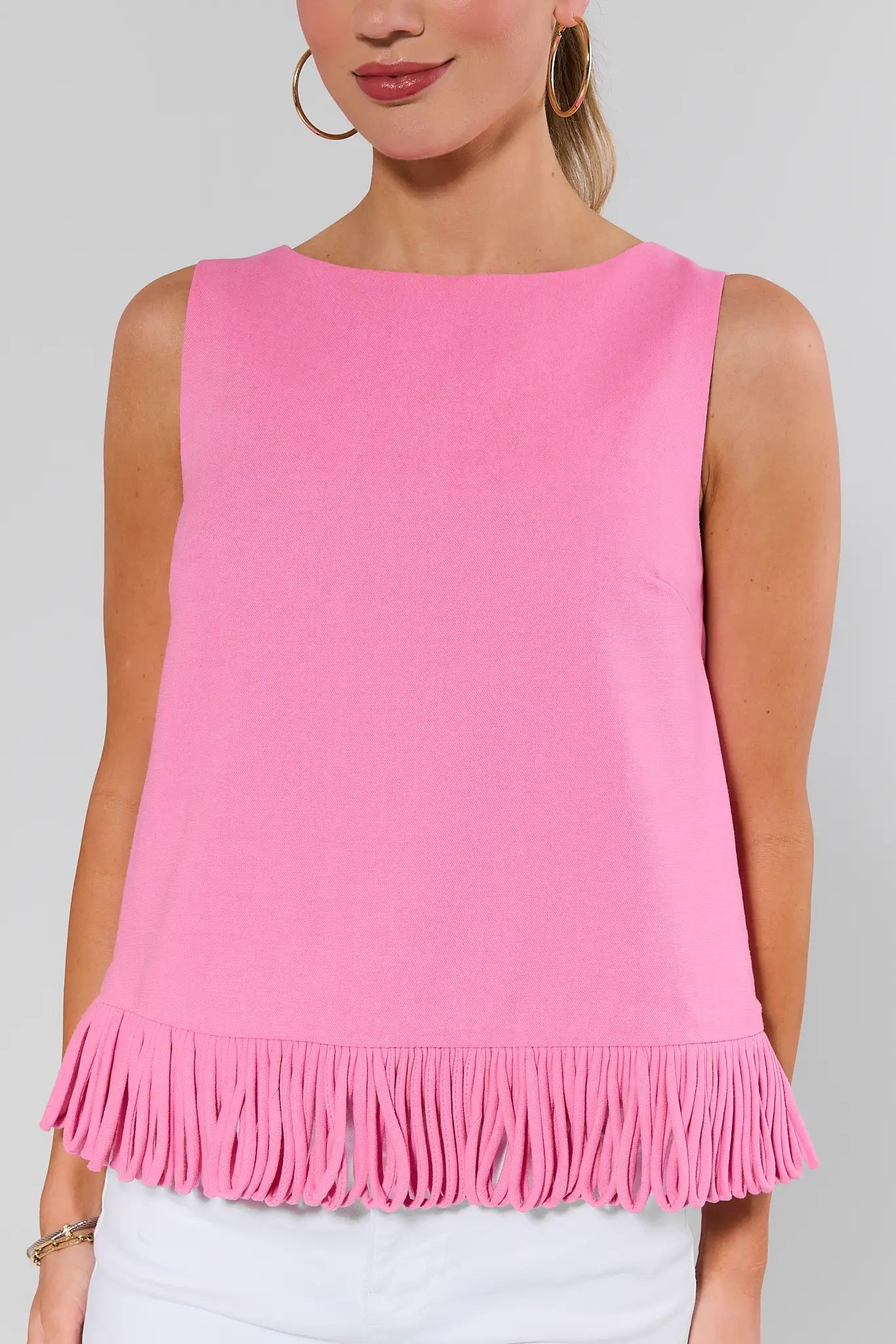 close up Woman wearing a pink sleeveless top with fringe details on a gray background