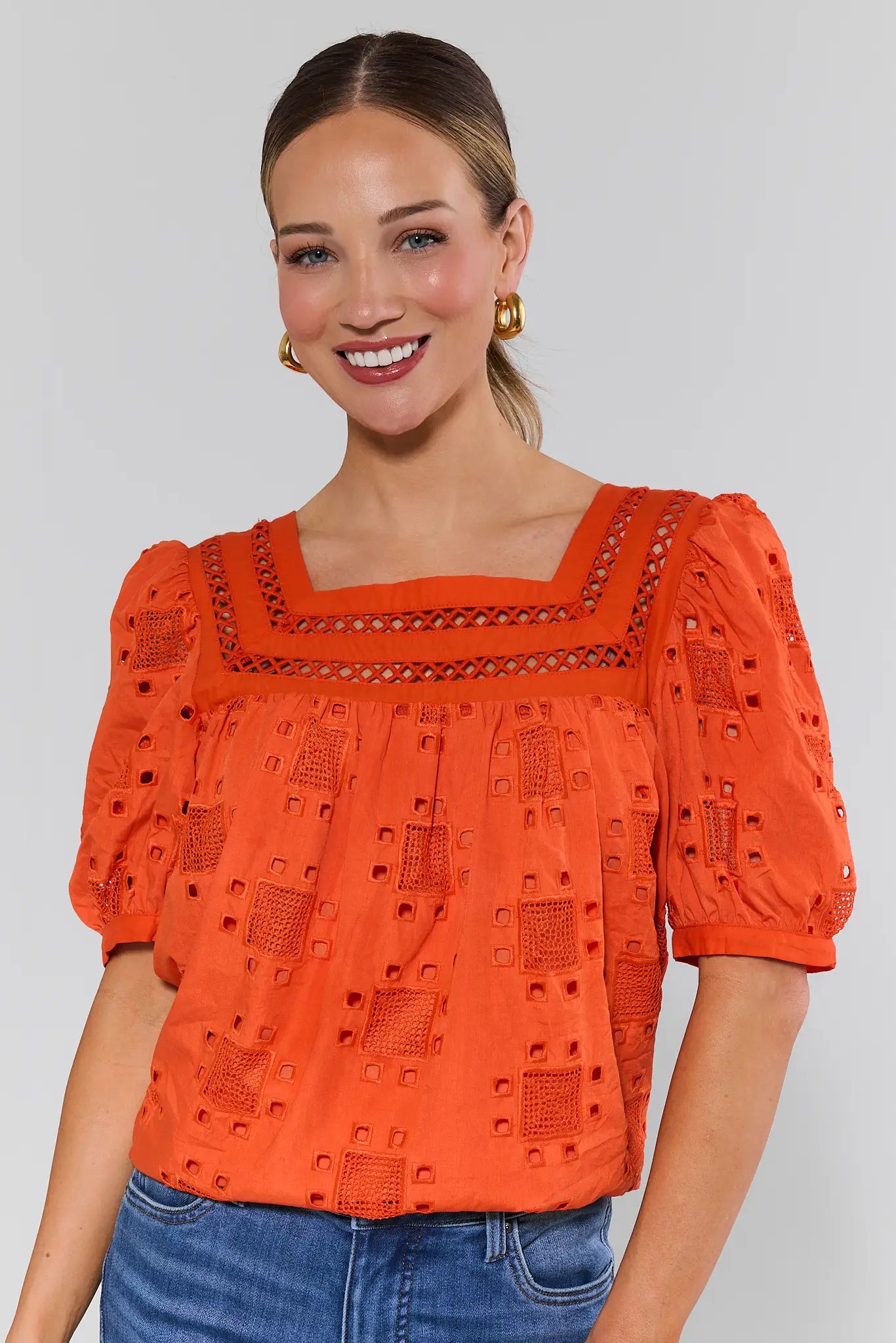 Woman wearing an orange blouse with a white background