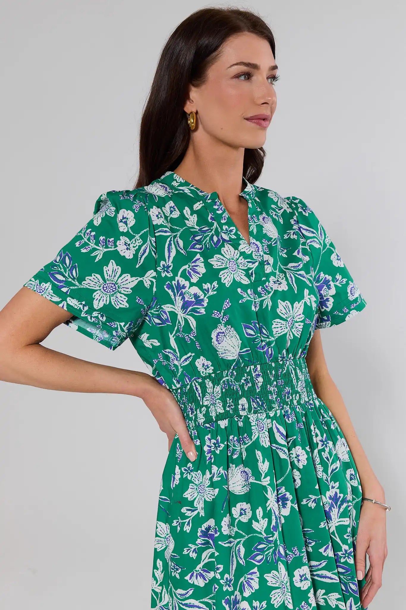 close up Woman wearing a green floral dress against a plain background