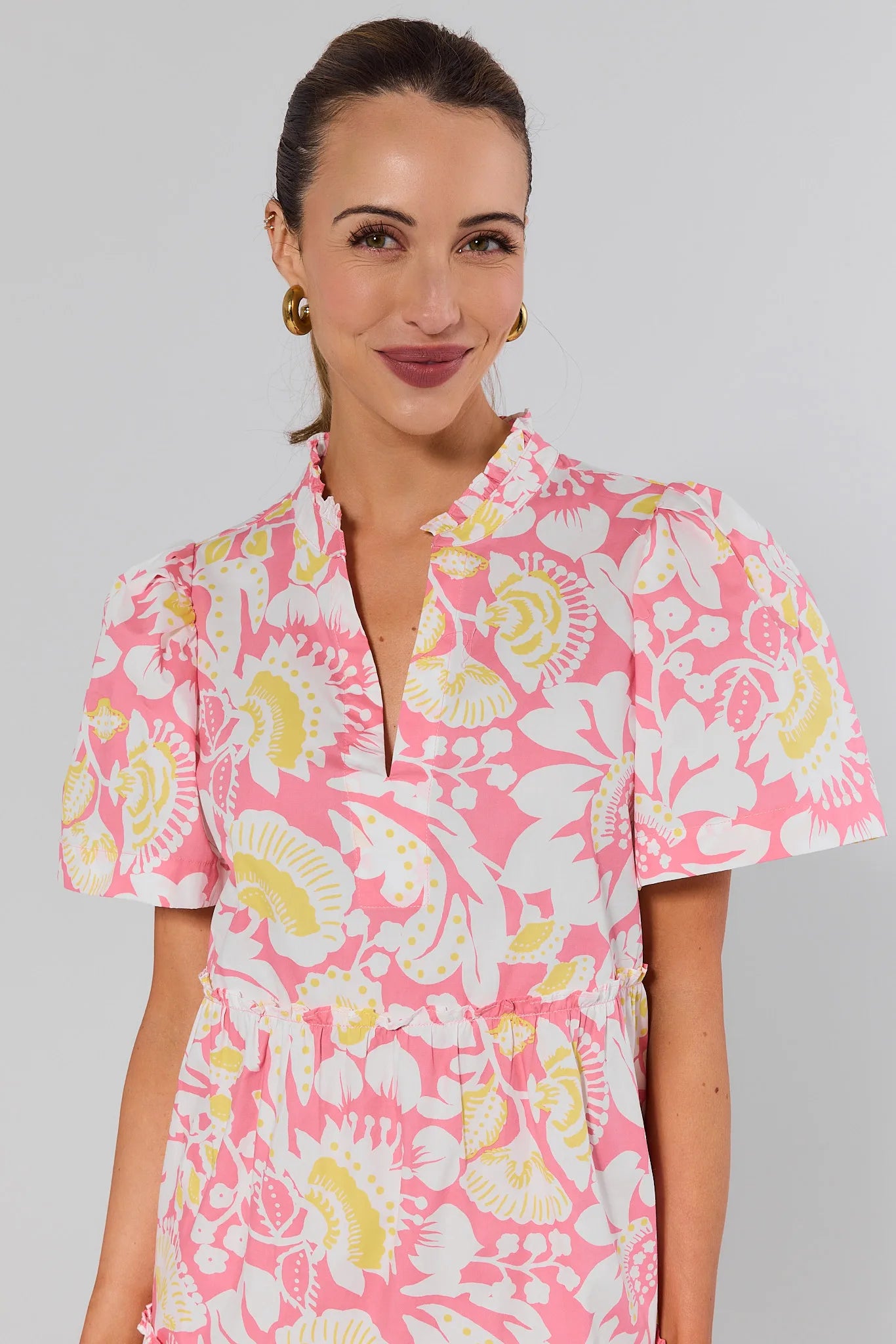 close up Woman wearing a pink floral dress against a gray background
