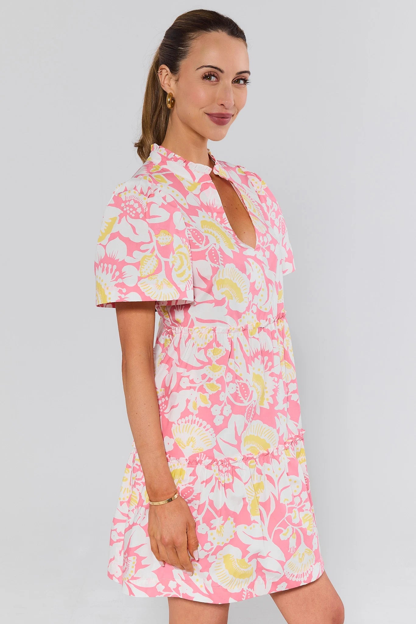 side shot Woman wearing a pink floral dress against a gray background