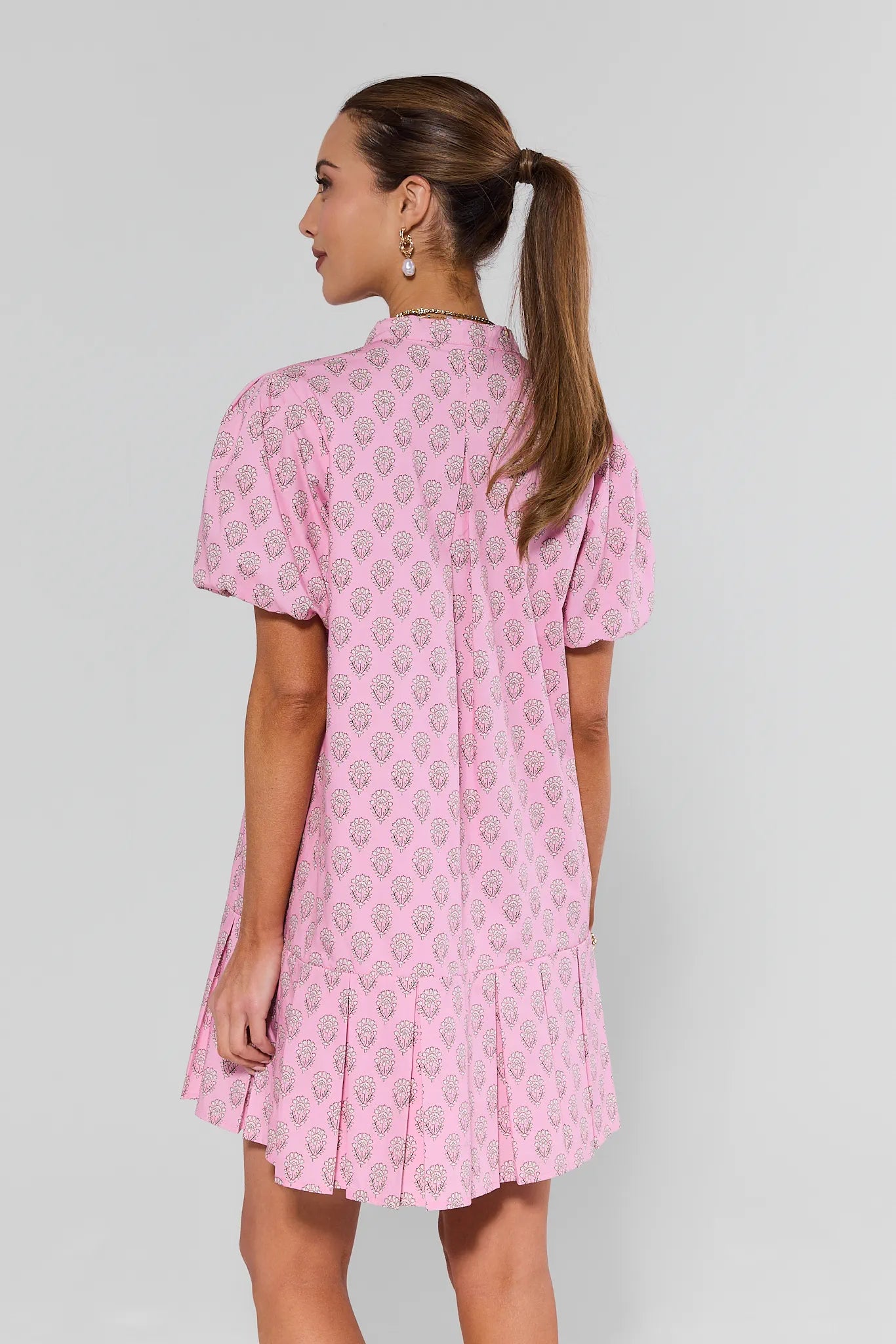 Woman wearing a pink patterned dress on a grey background