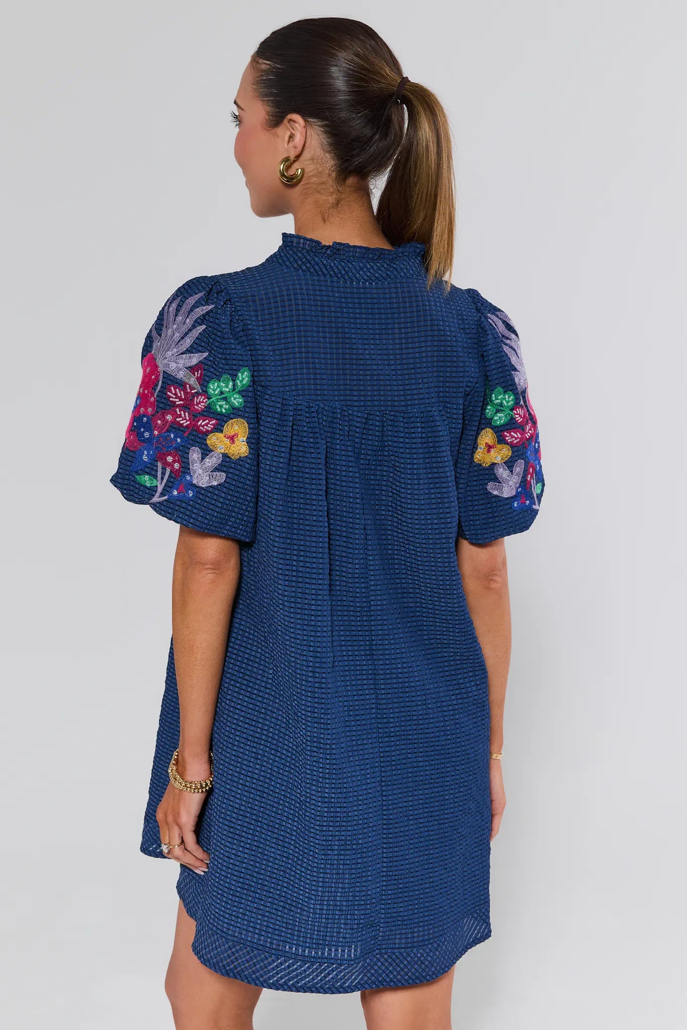 Woman wearing a blue dress with floral embroidery on a white background